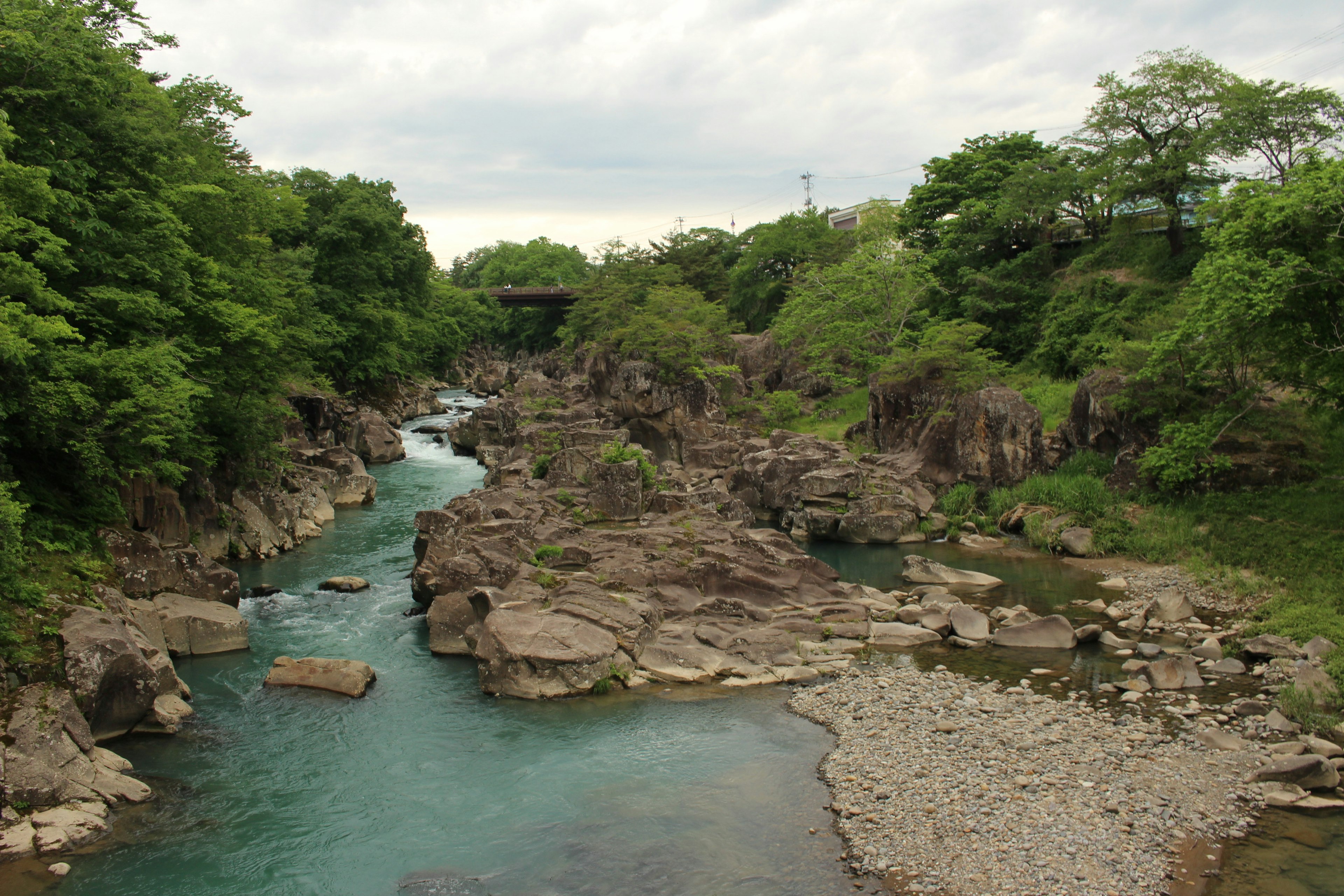 Ein ruhiger Fluss, der durch felsiges Terrain fließt, umgeben von üppigem Grün