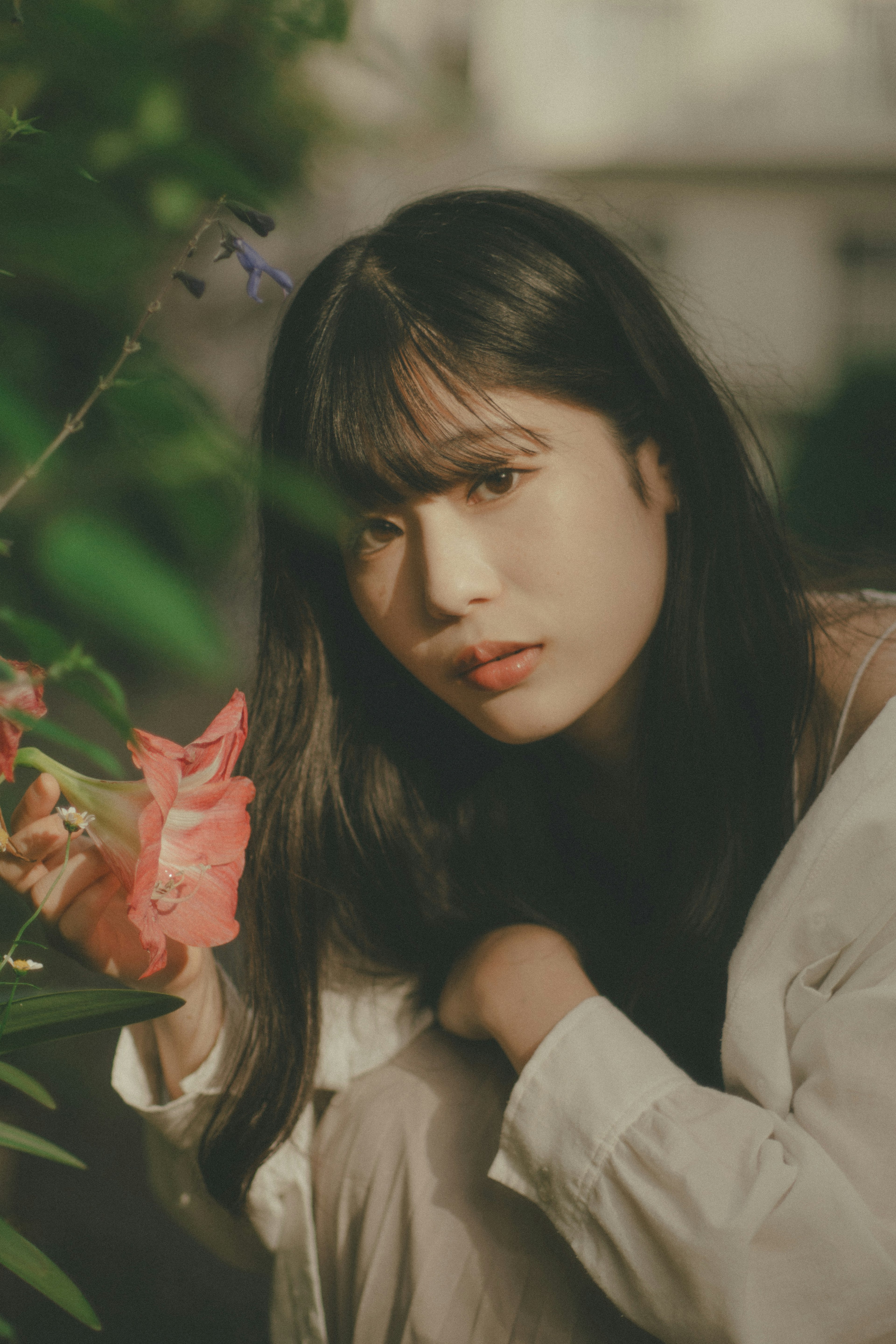 Retrato de una mujer sosteniendo flores contra un fondo verde