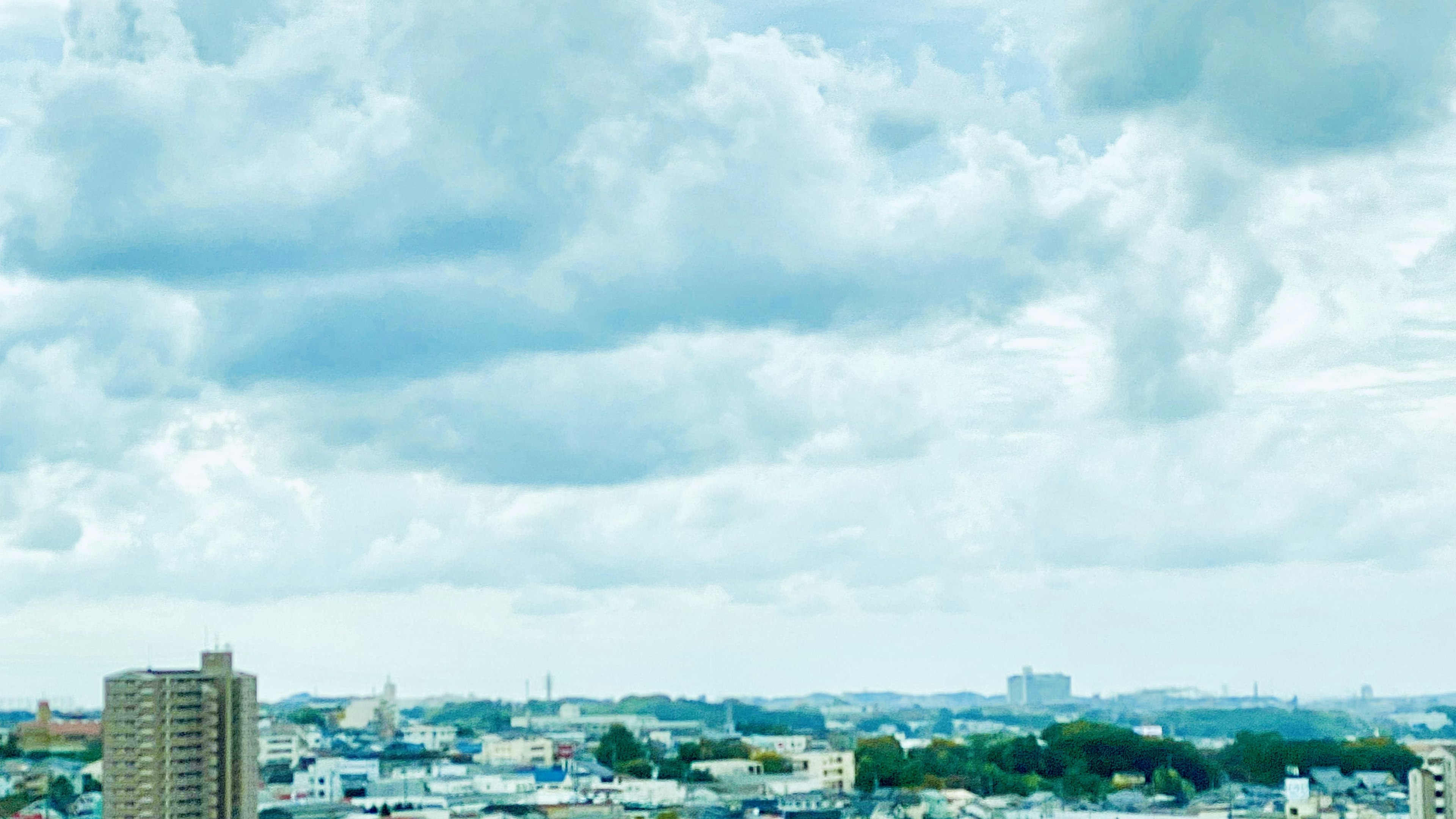 Eine Stadtlandschaft mit blauem Himmel und Wolken sowie Hochhäusern und Wohngebieten