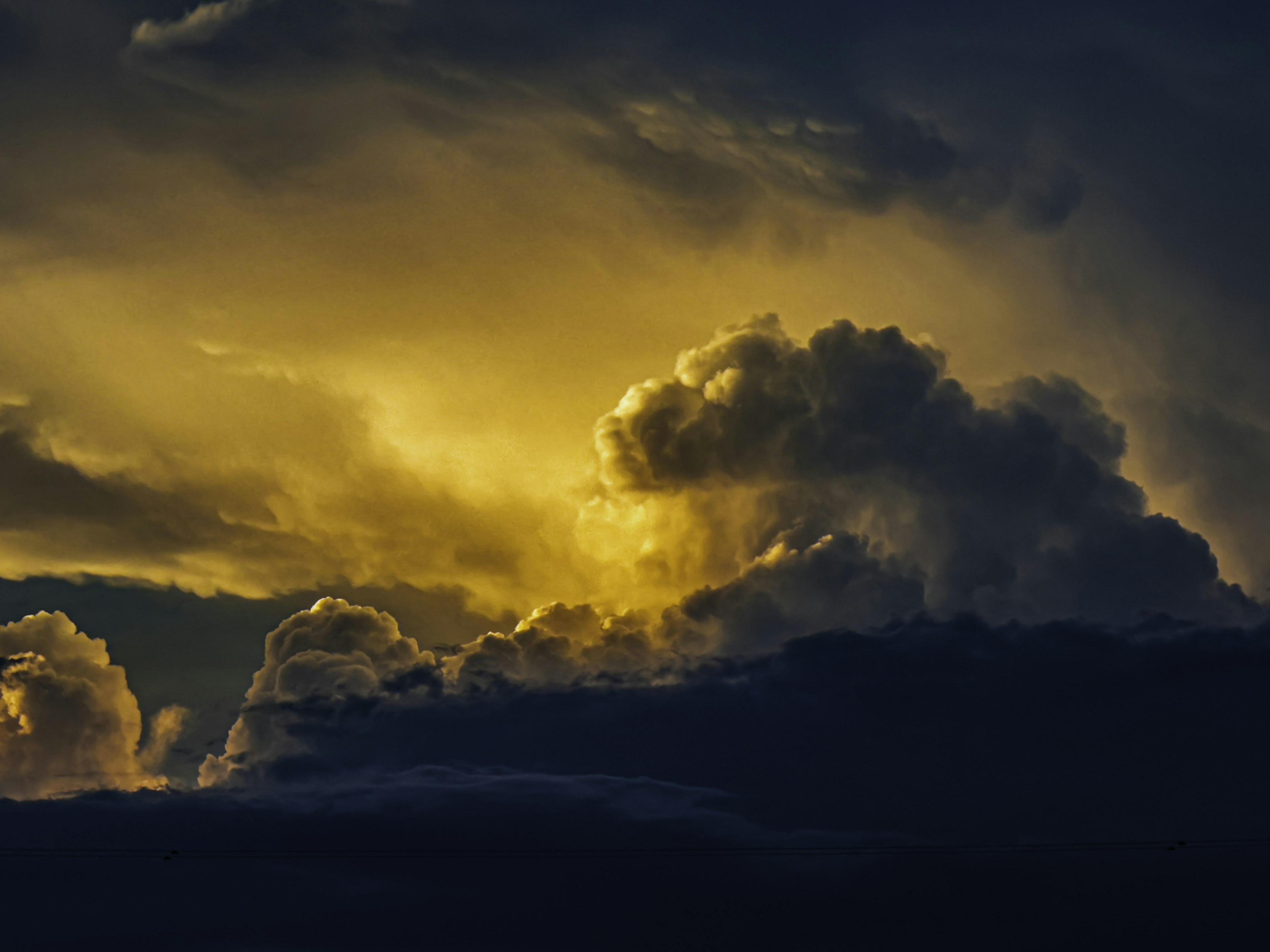 Dramatischer Himmel mit dunklen Wolken, die von goldenem Licht erleuchtet werden