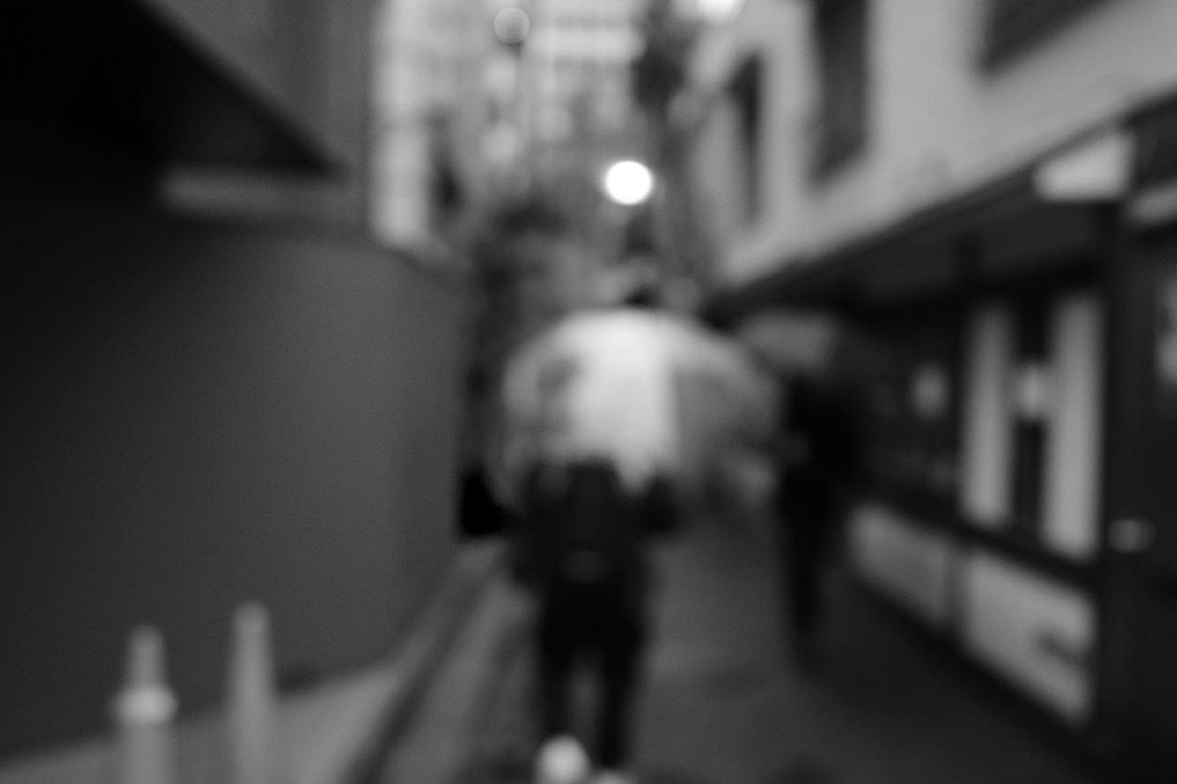 Silhouette d'une personne tenant un parapluie dans une ruelle floue