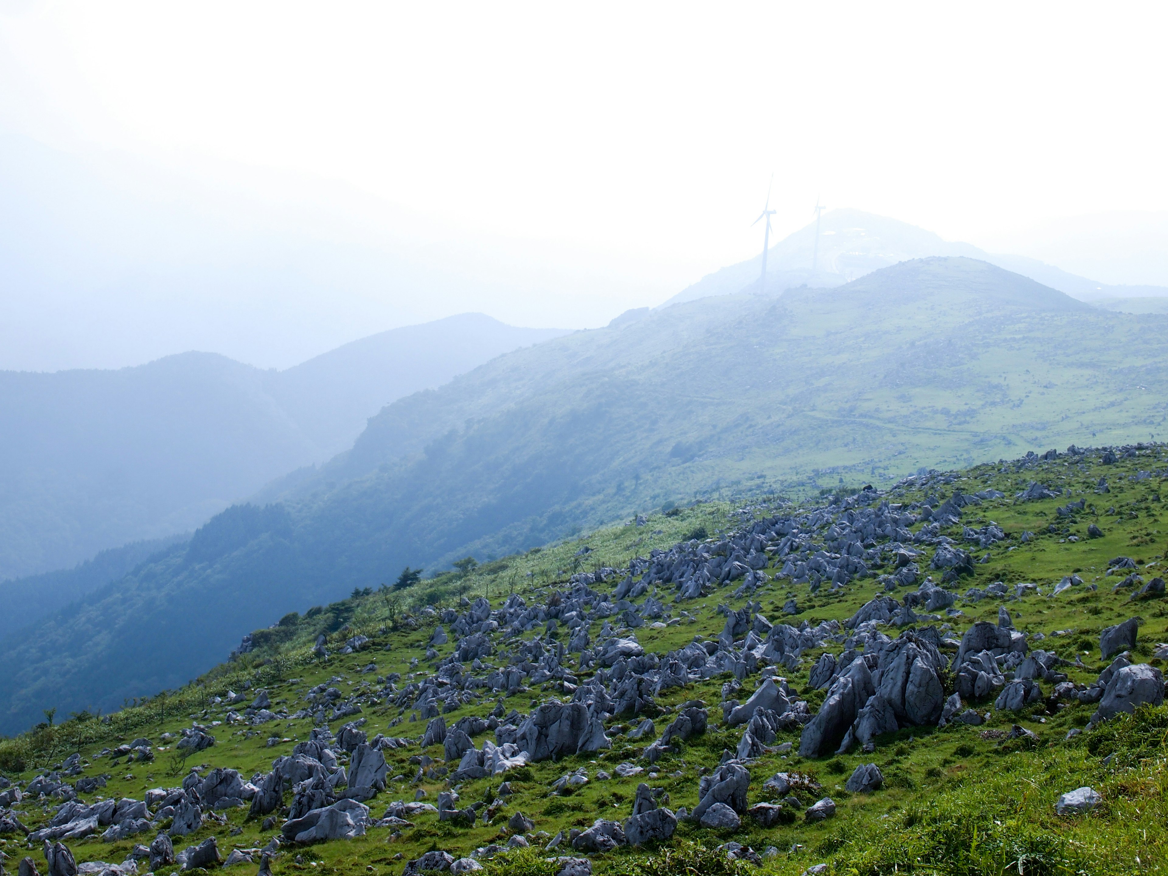 Foggy mountain landscape with rocky terrain and greenery