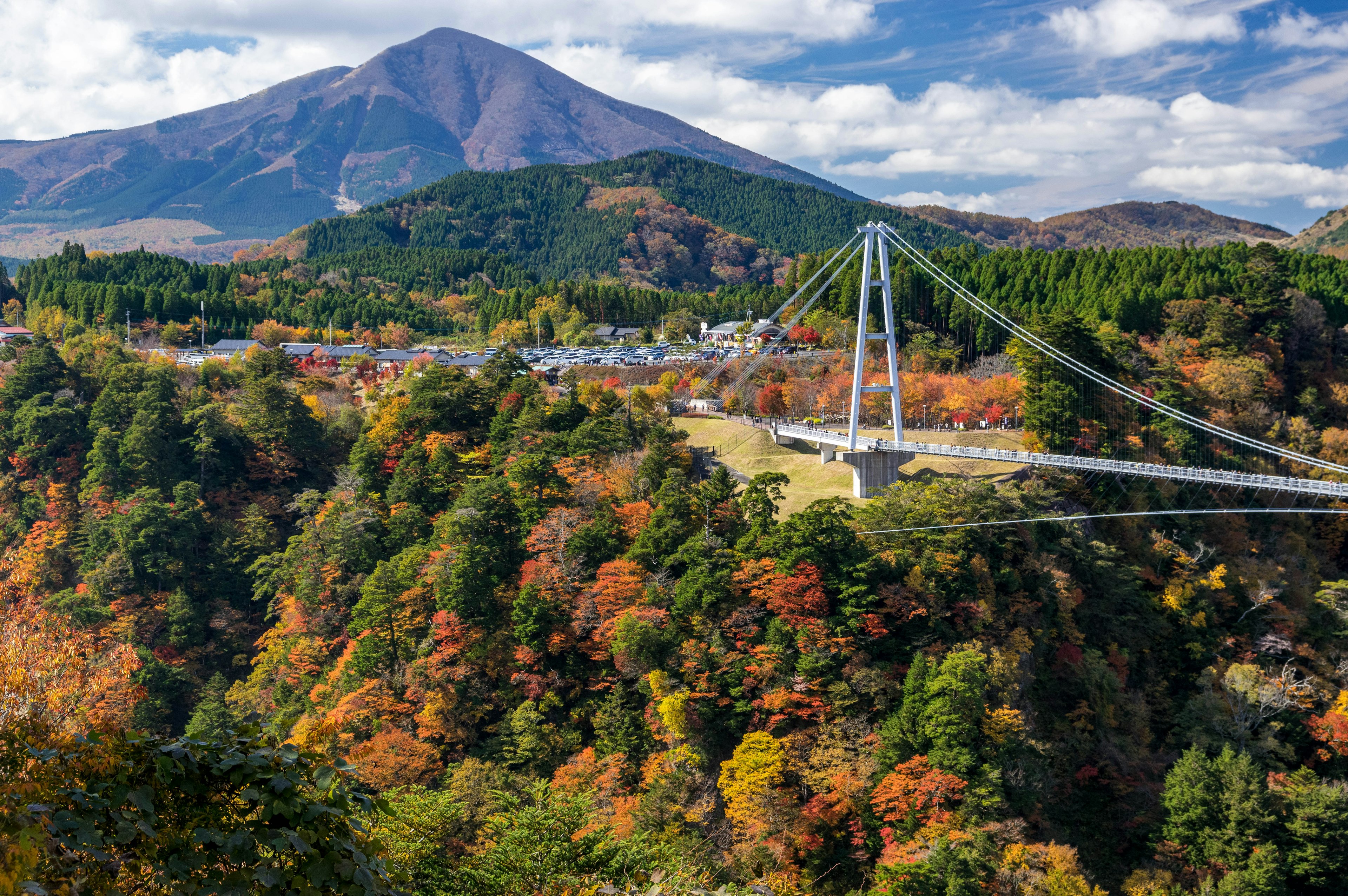 Vista escénica de un puente colgante rodeado de follaje otoñal y montañas