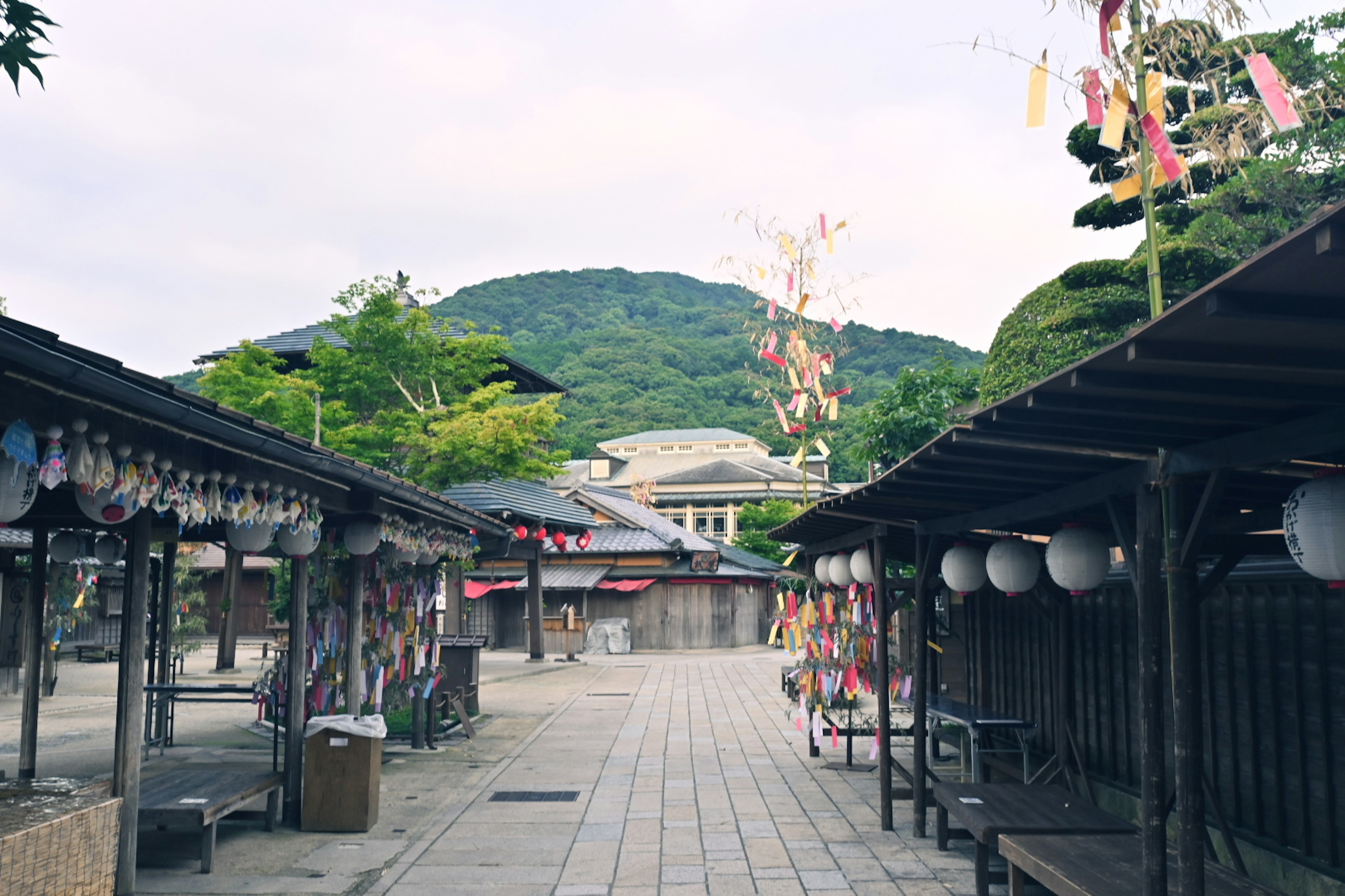 山を背景にした静かな市場通りに並ぶ屋台と提灯