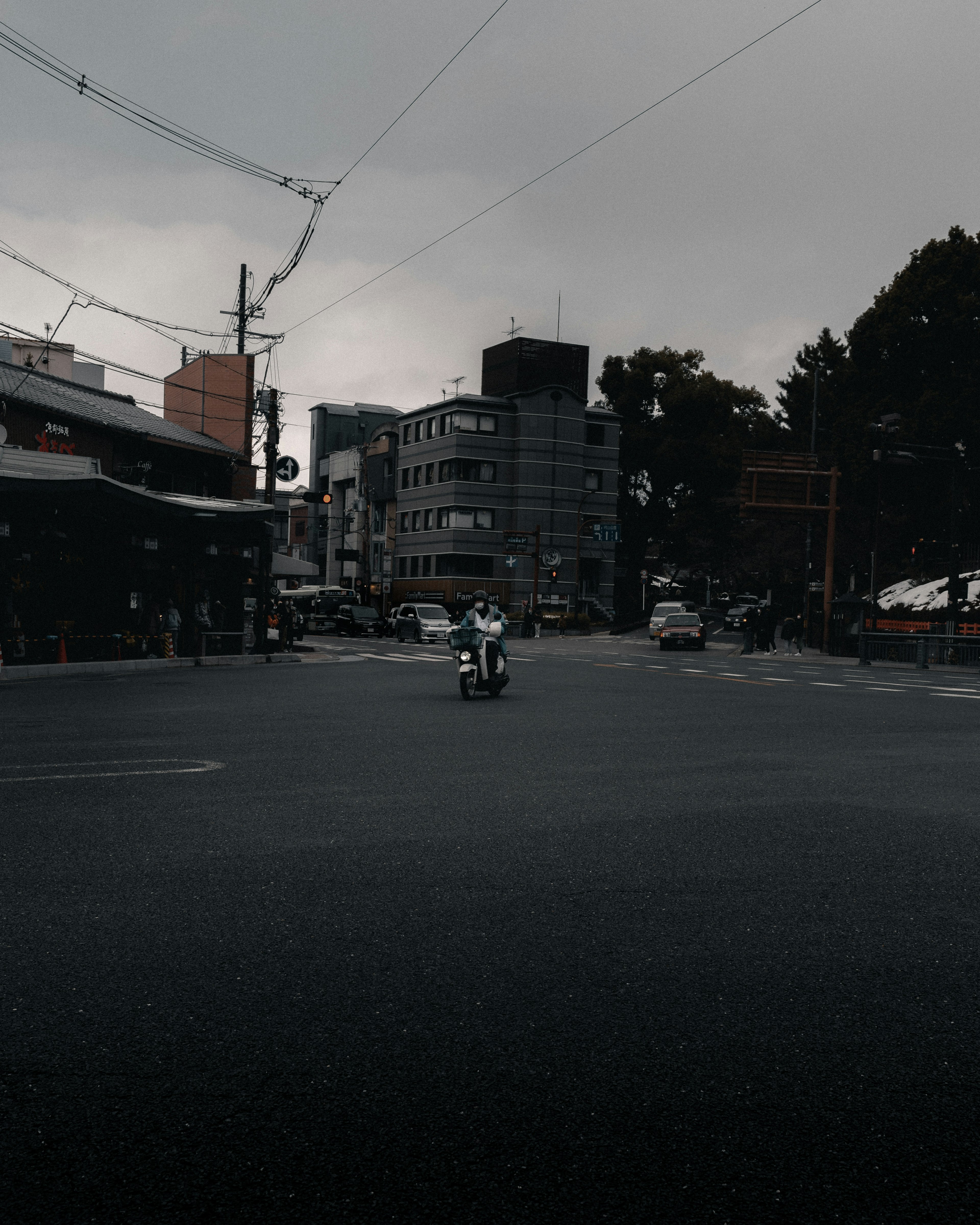 Motorcycle rider at an urban intersection under rainy skies with surrounding buildings