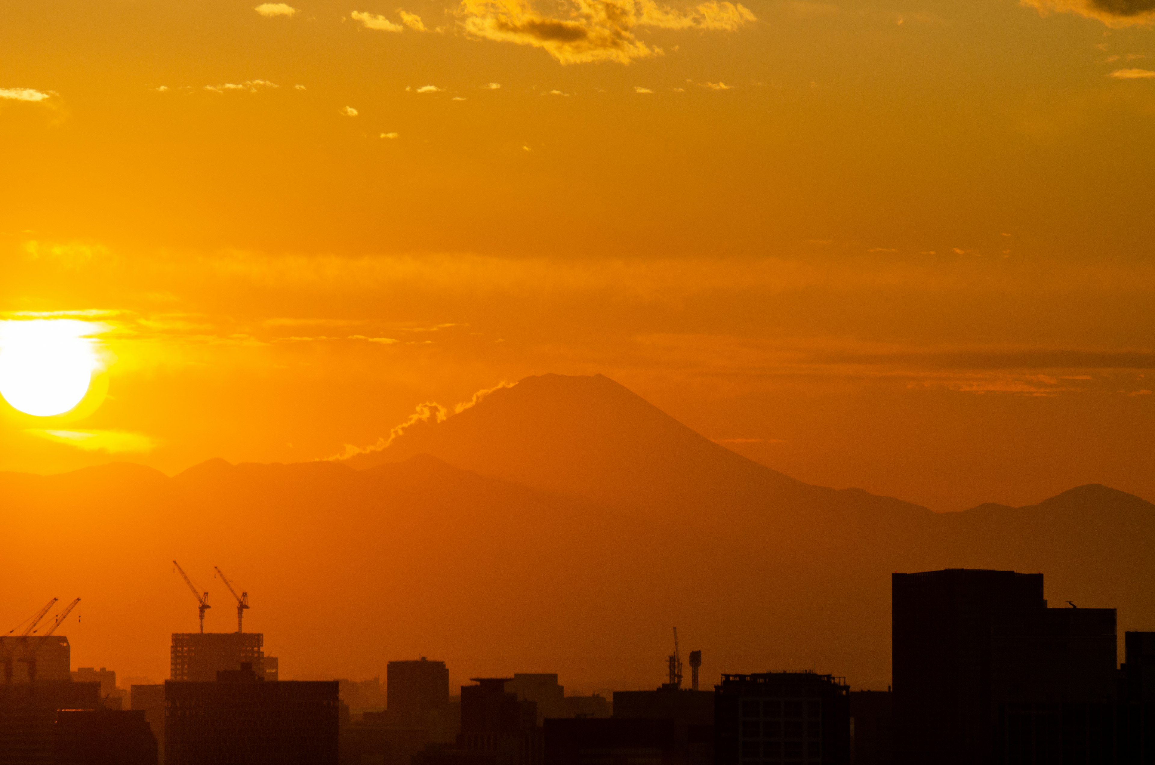 日落景觀與山脈和城市輪廓