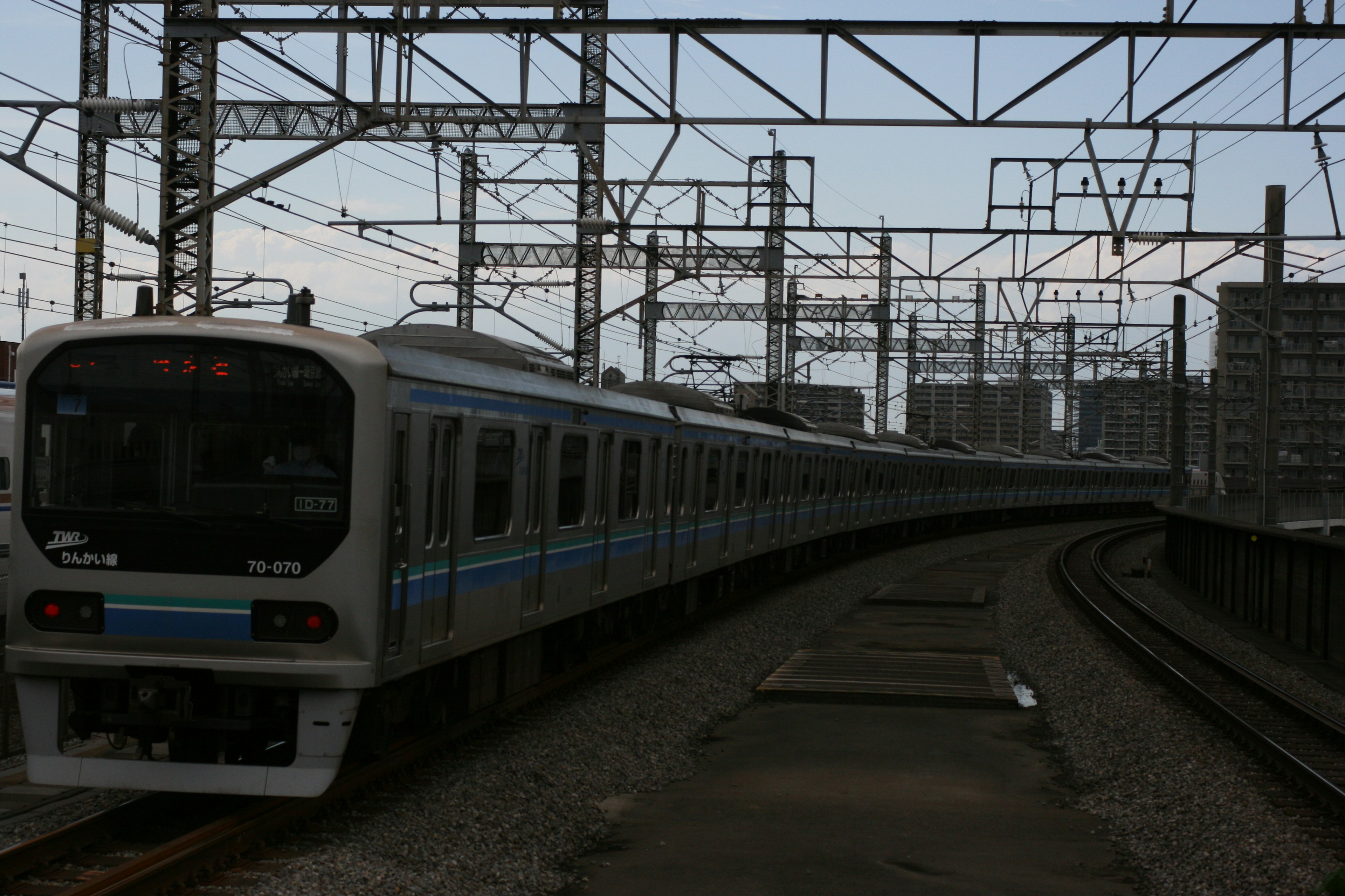 電車が曲がる線路と高架の電線が見える風景