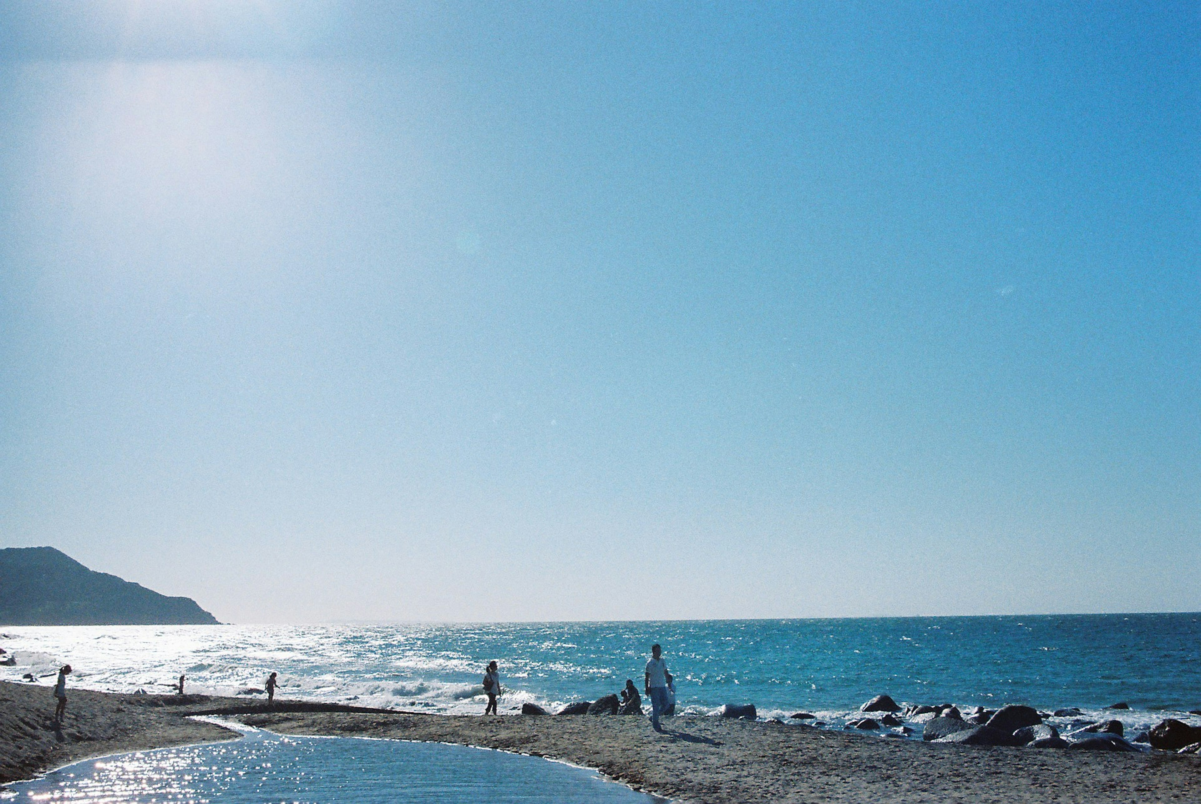 Scena di spiaggia con cielo blu e oceano persone che si divertono sulla riva