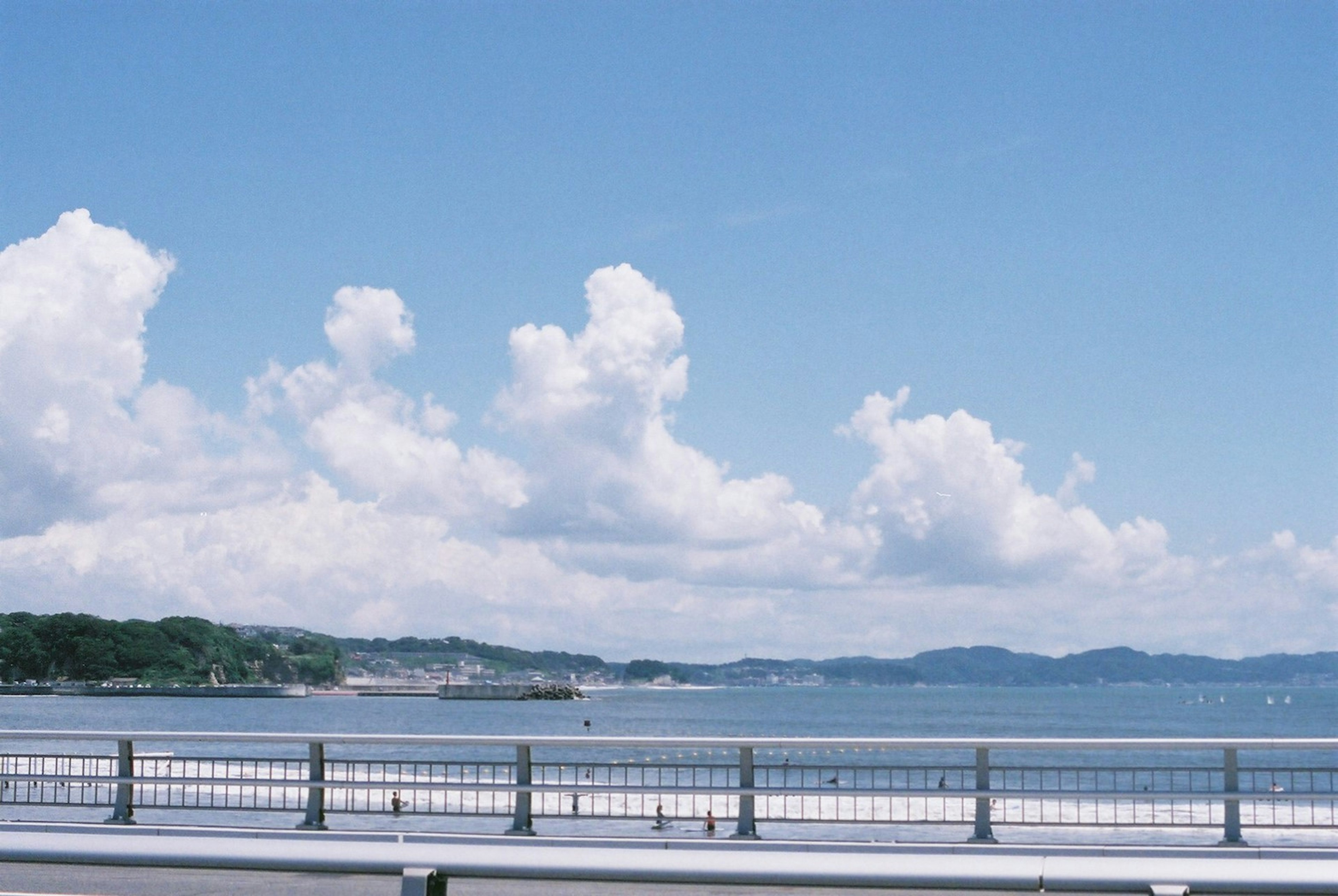 Vue pittoresque du ciel bleu et des nuages blancs au-dessus de la mer avec une rambarde au premier plan