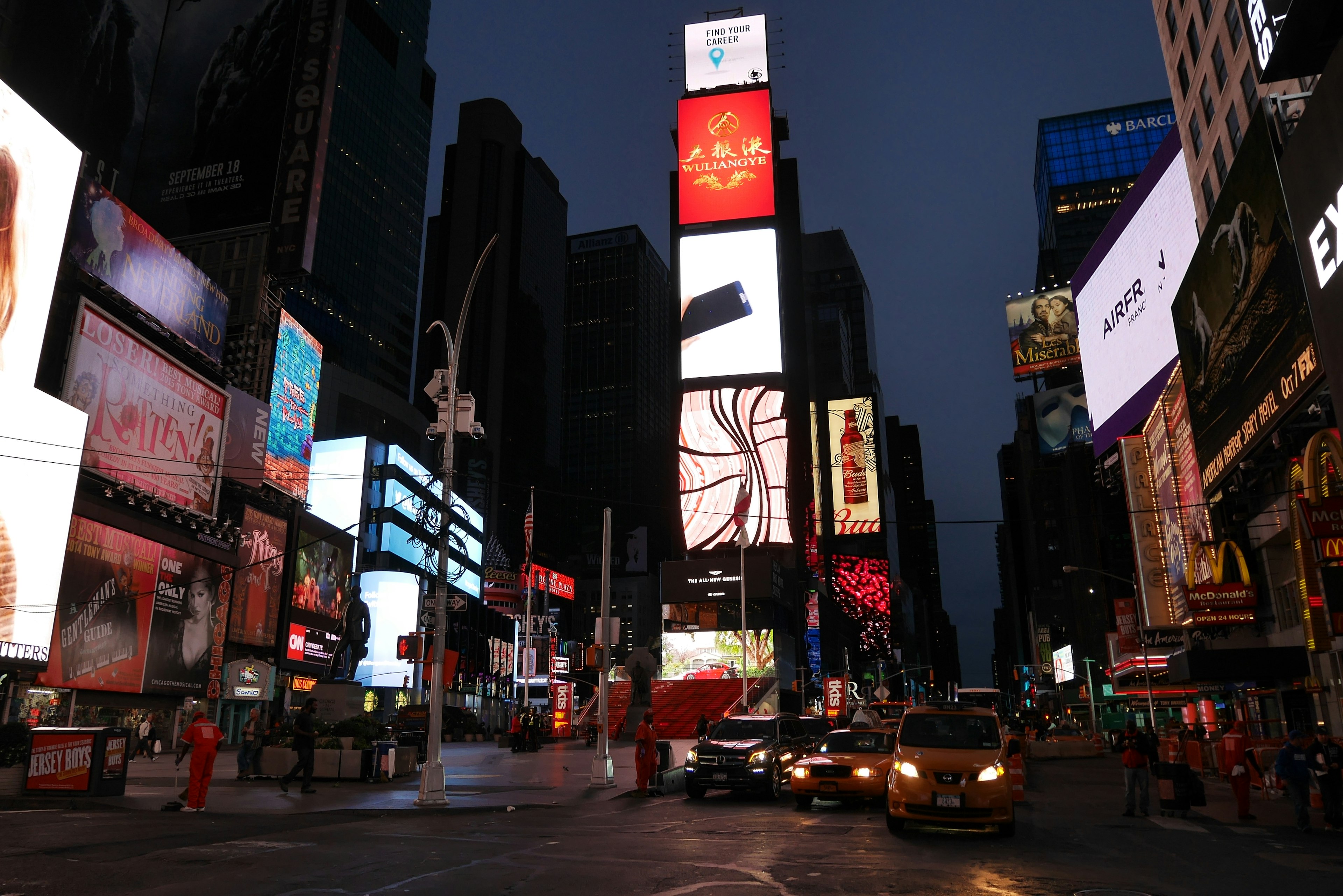 Times Square bei Nacht mit hellen Neon-Schildern und Fahrzeugen