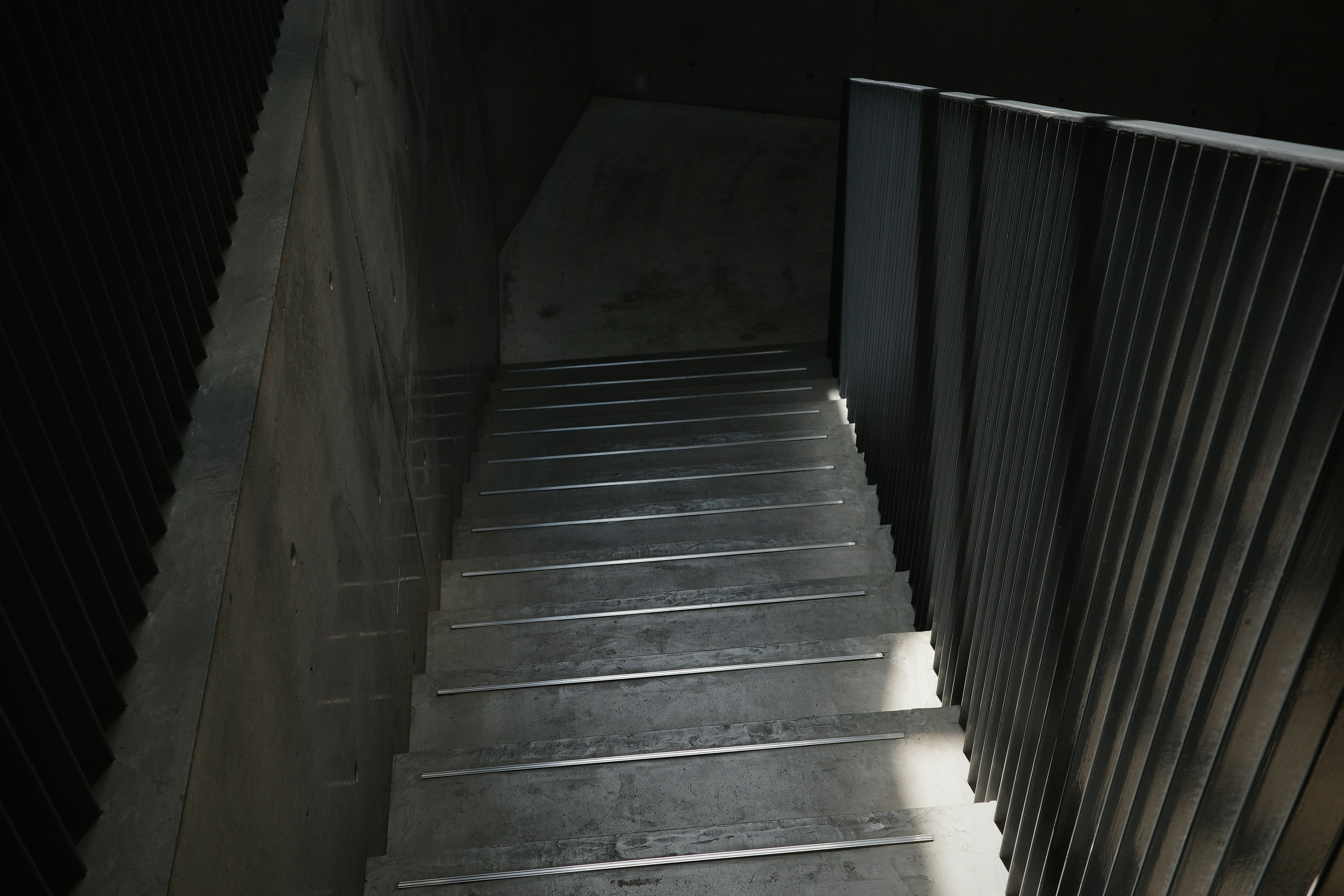 Escalera de metal con pared de concreto en un espacio oscuro vista desde arriba