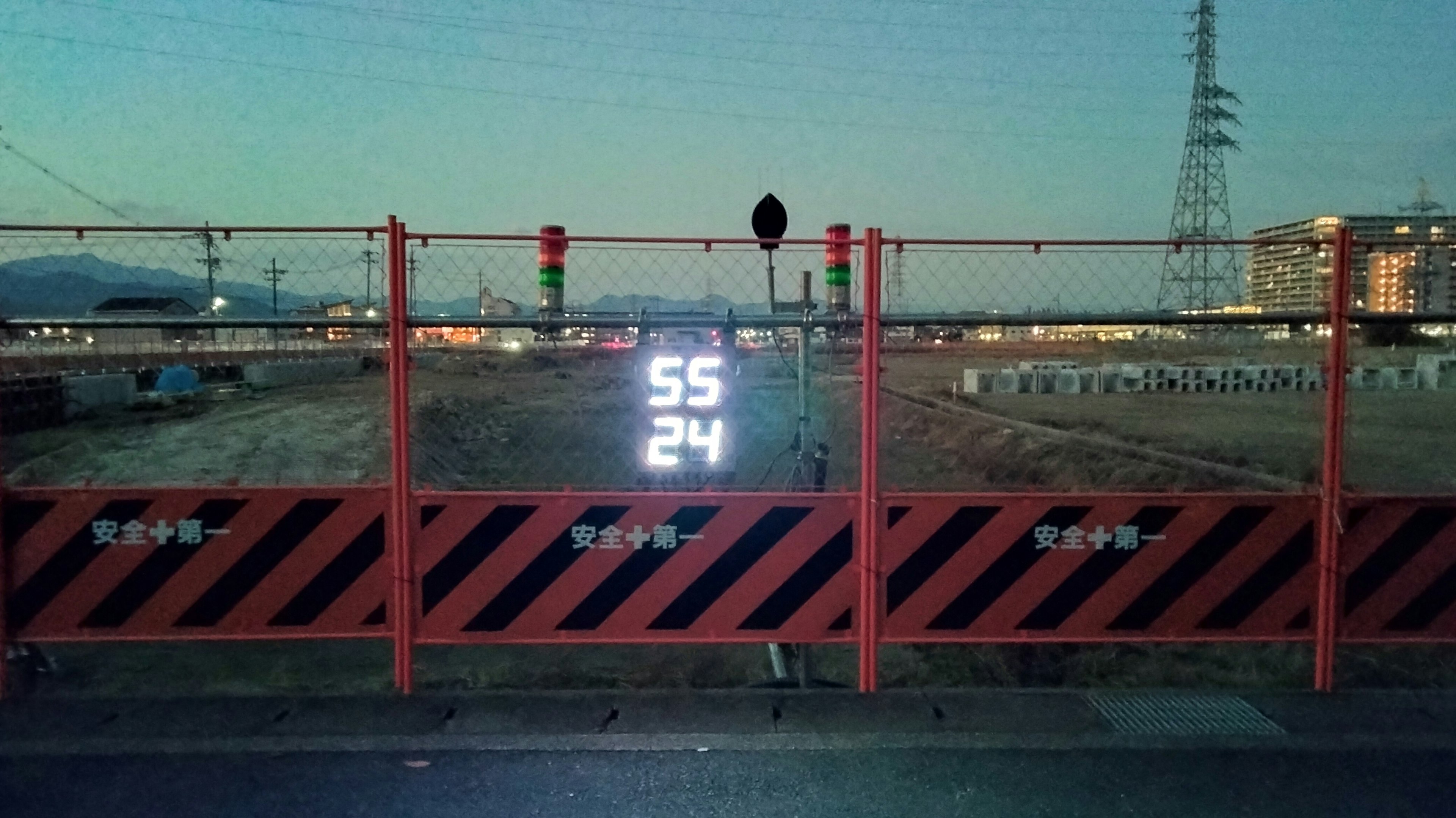 Pantalla digital que muestra los números 55 y 24 en un sitio de construcción con barricadas rojas