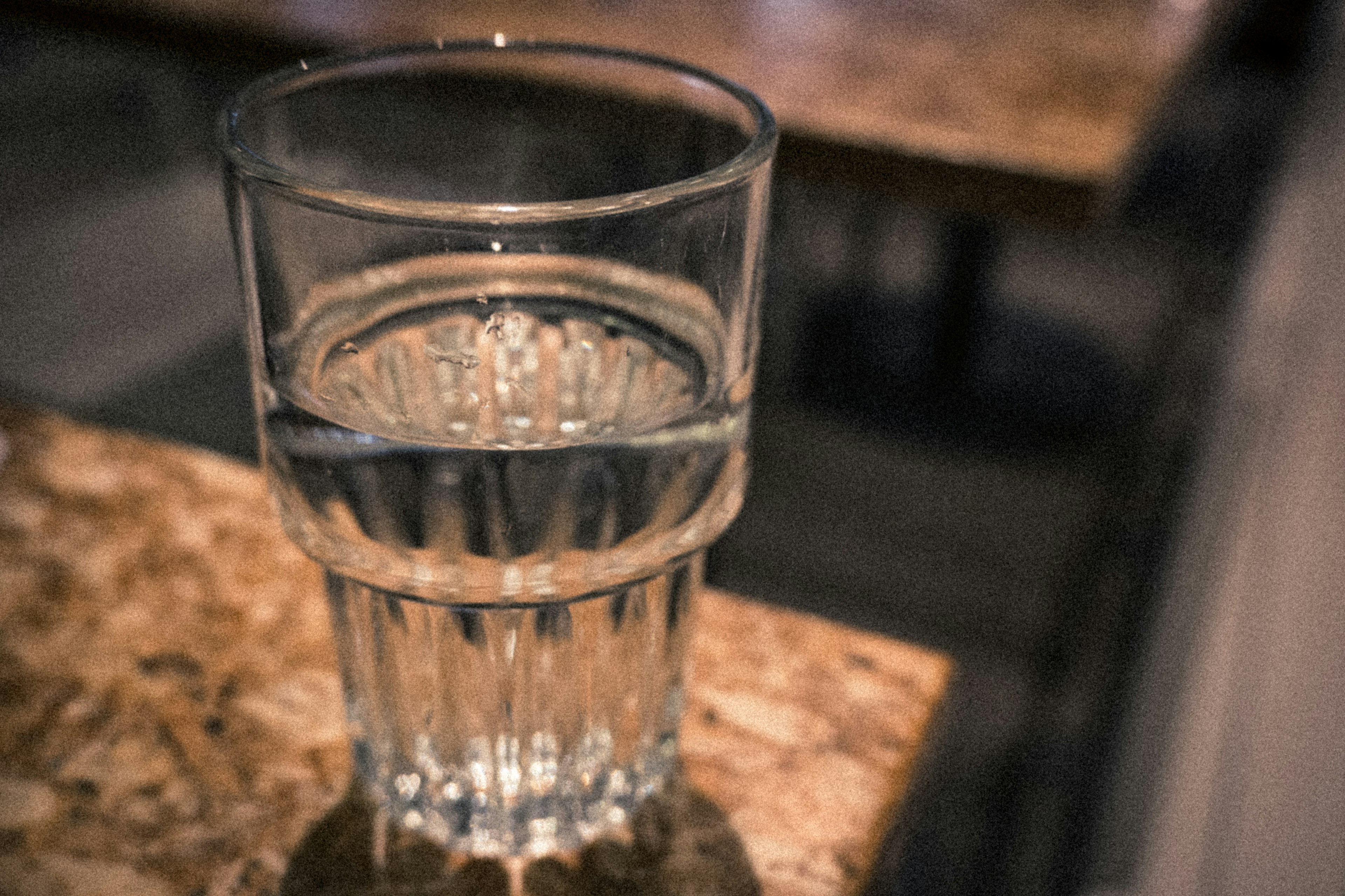 A clear glass of water placed on a table surface