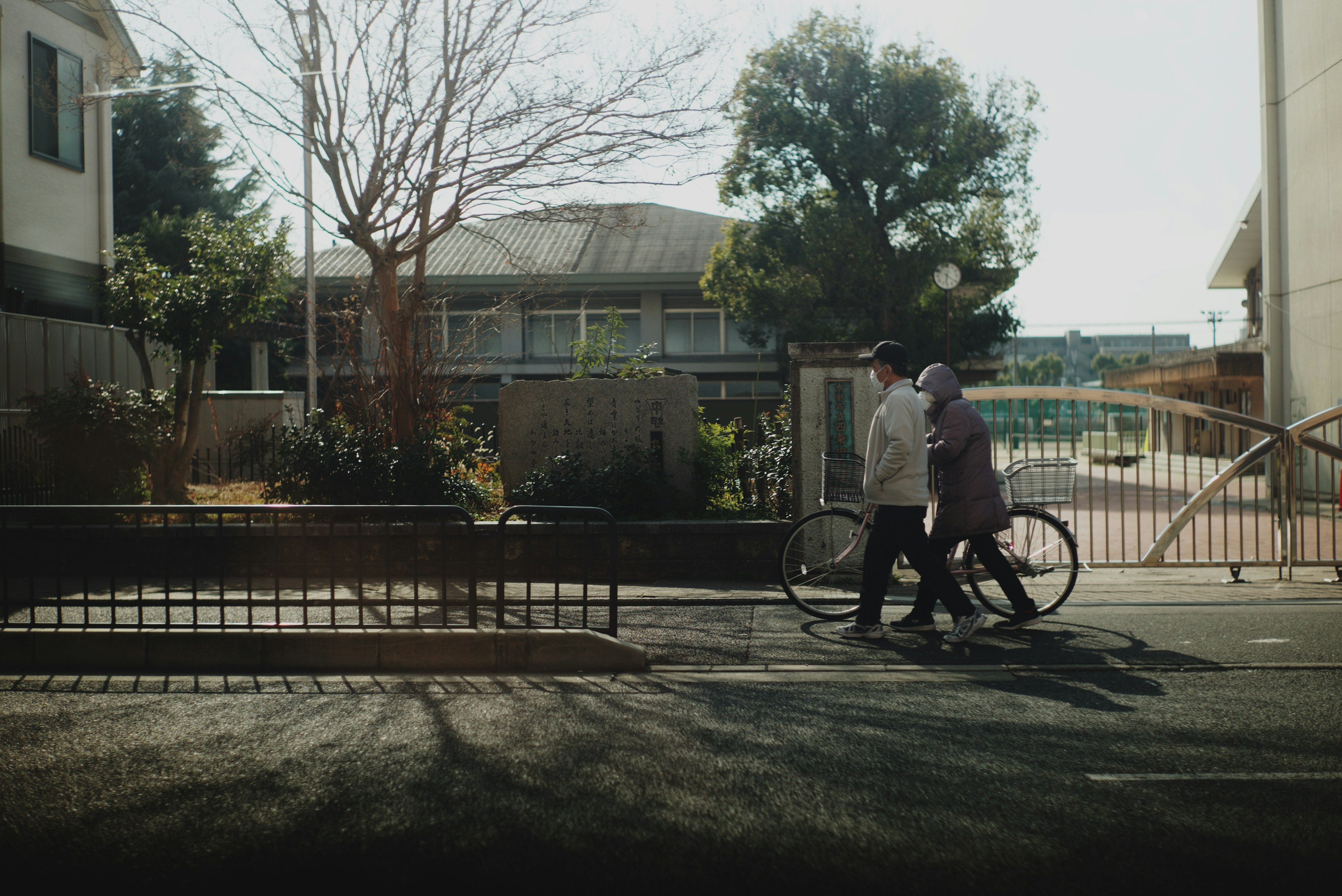 Two people walking with a bicycle in a quiet street scene