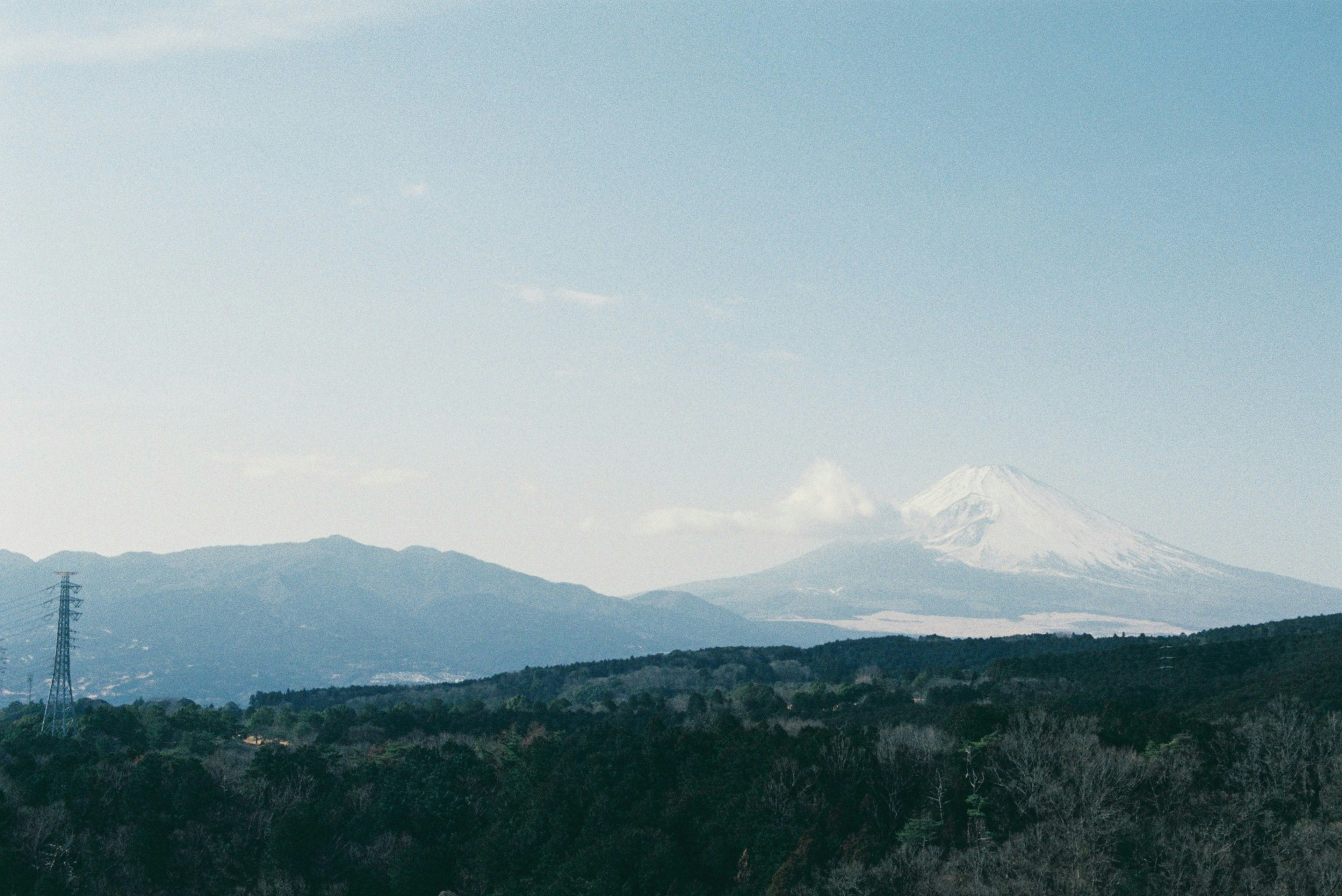 青空の下に広がる山々と雪をかぶった山の風景