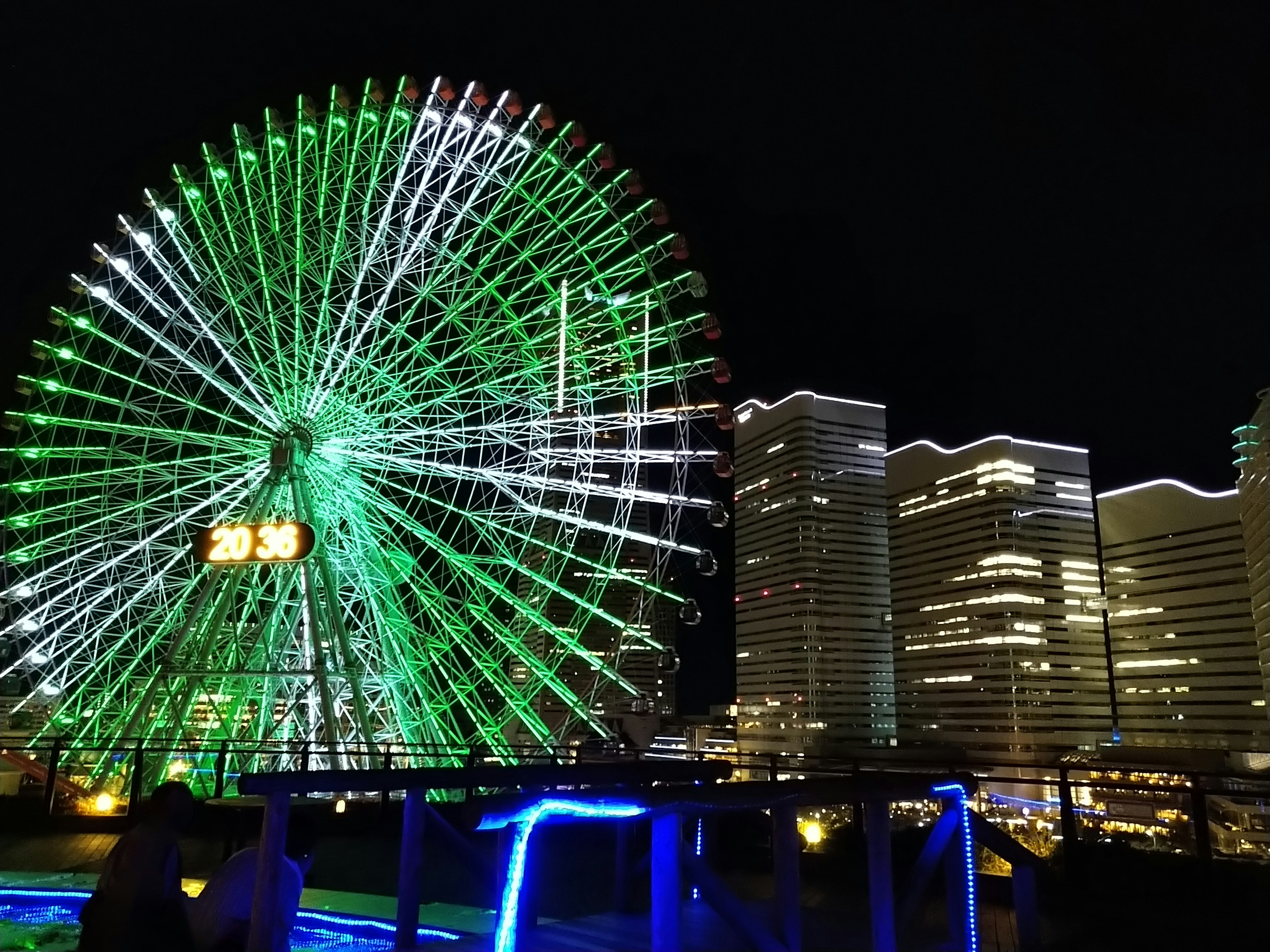 夜景中的摩天轮和摩天大楼，特色是绿色灯光