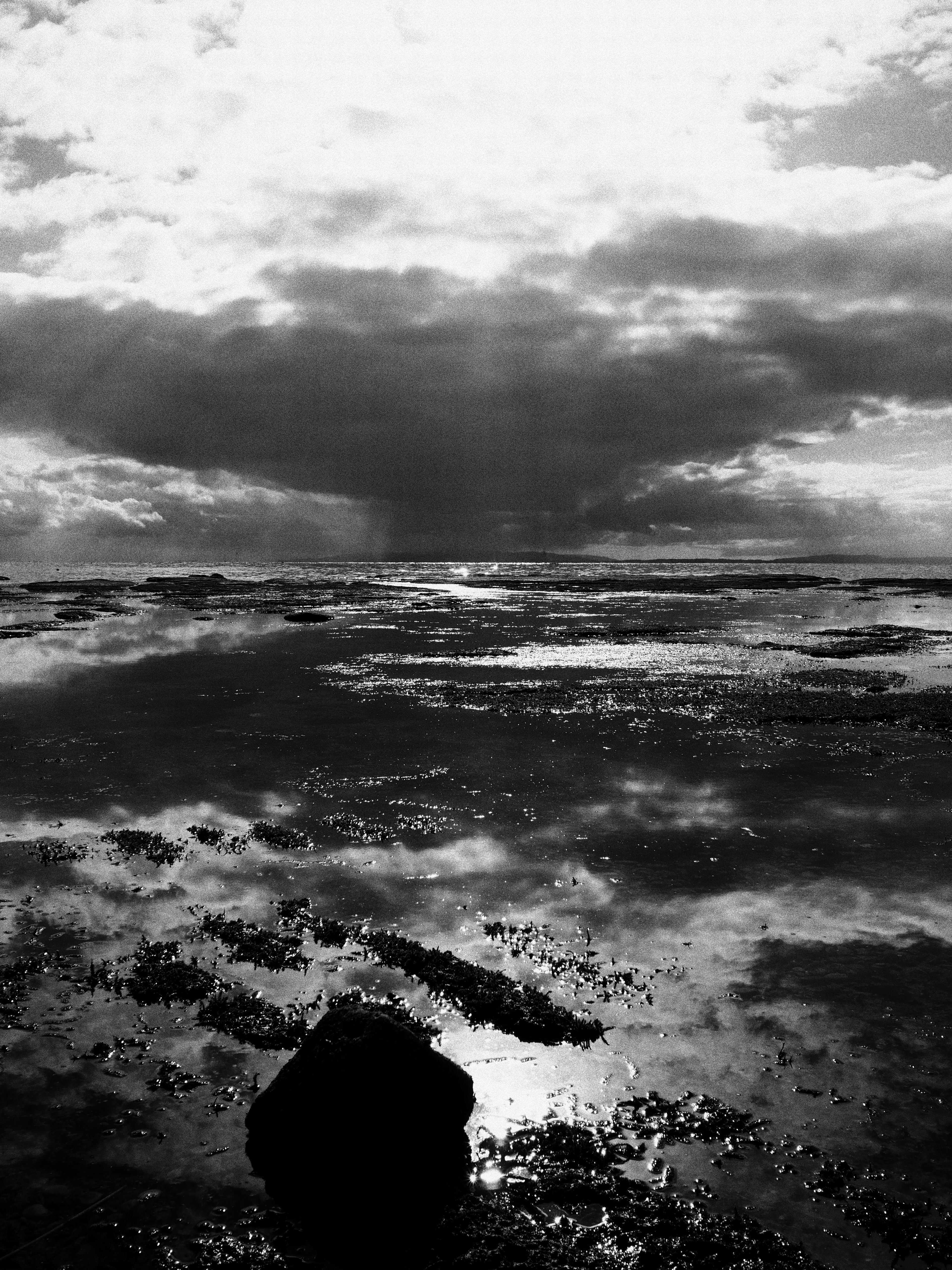 Paisaje en blanco y negro con océano y nubes dramáticas