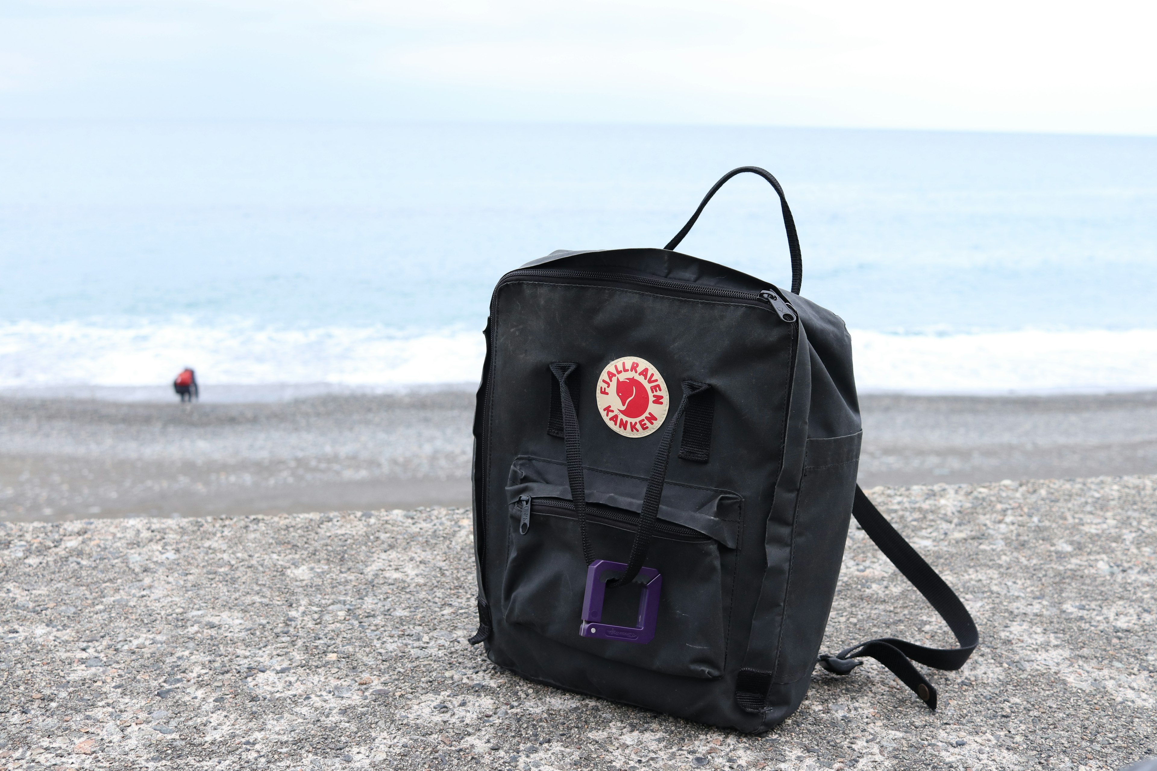 Black backpack placed on the beach with sea in the background