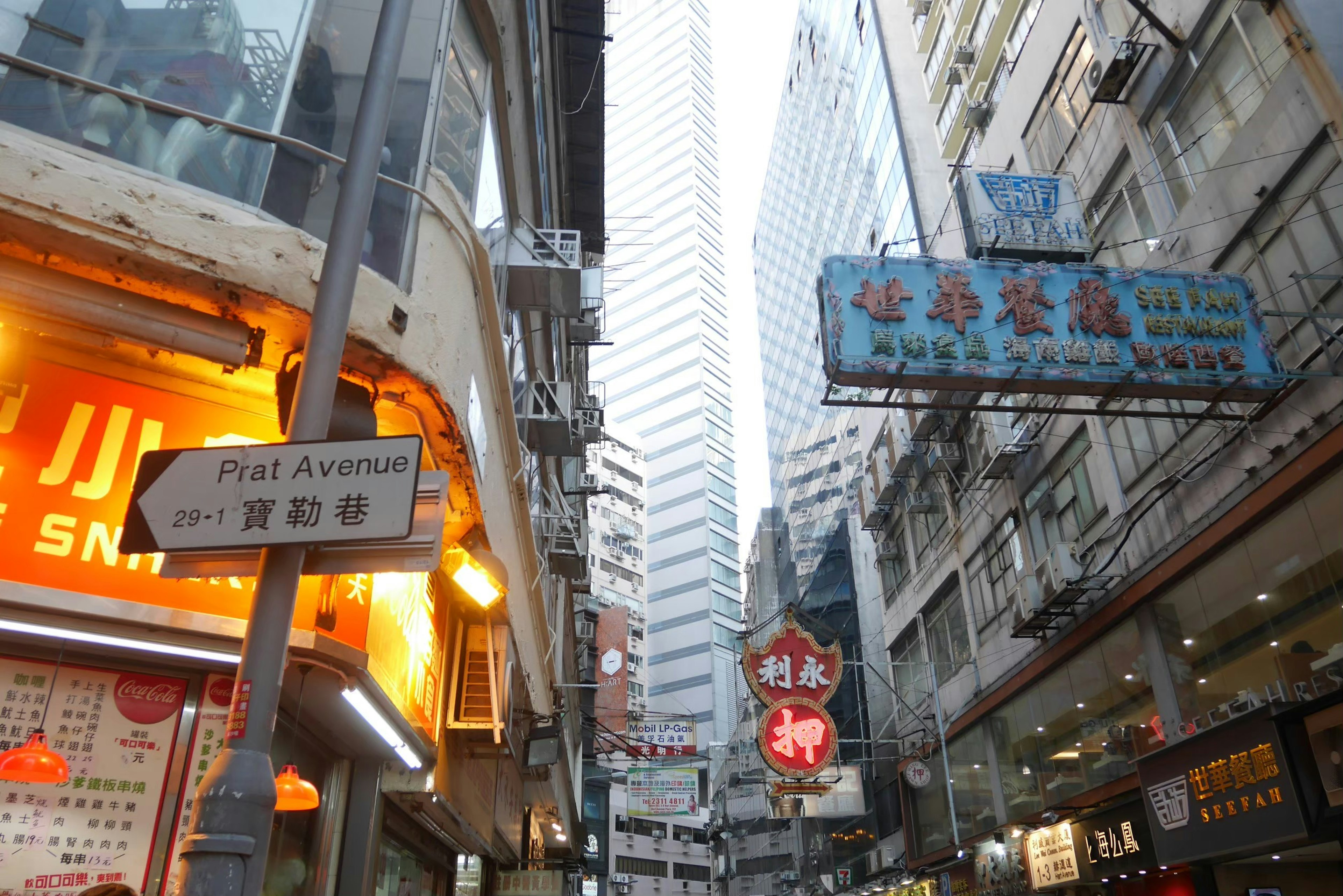 Jalan sempit di Hong Kong dengan papan nama neon dan gedung pencakar langit