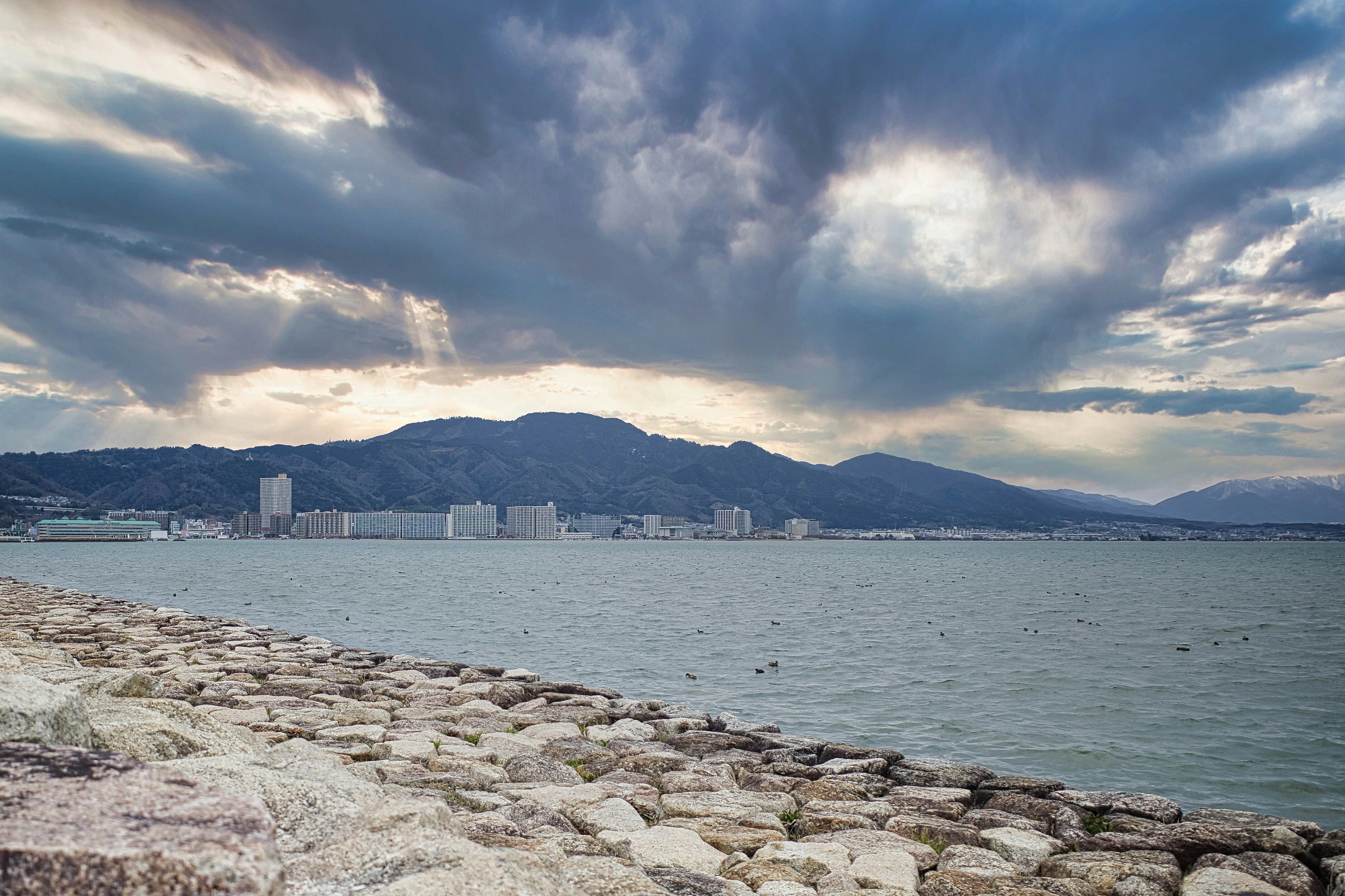 Scenic view of coastline and mountains under a dramatic cloudy sky