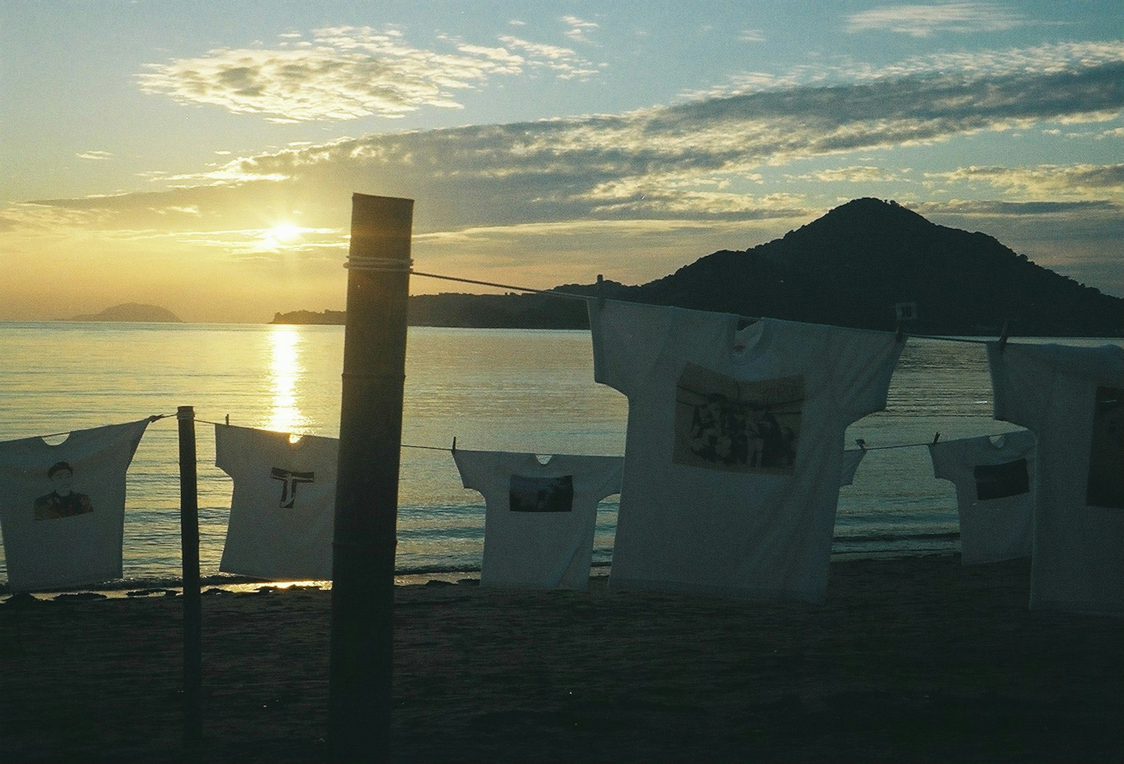 夕日を背景にした海岸で干された白いシャツ