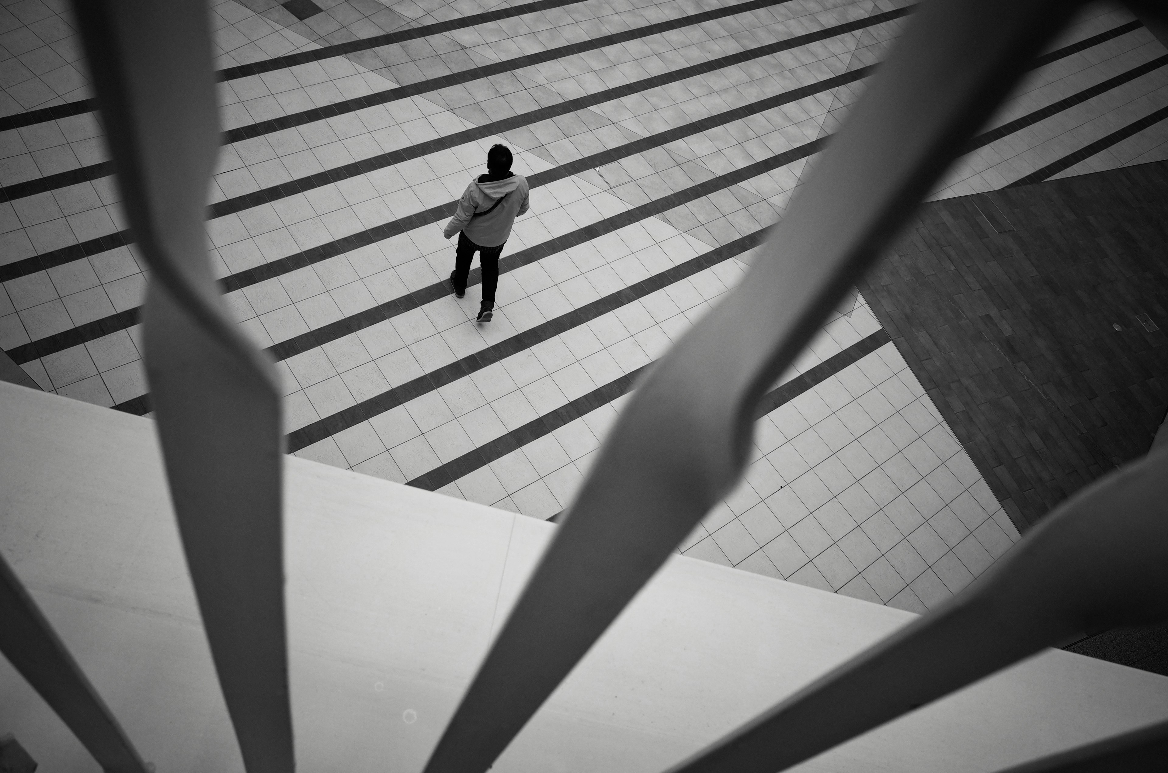 Una persona caminando sobre líneas diagonales en un entorno en blanco y negro con patrones destacados