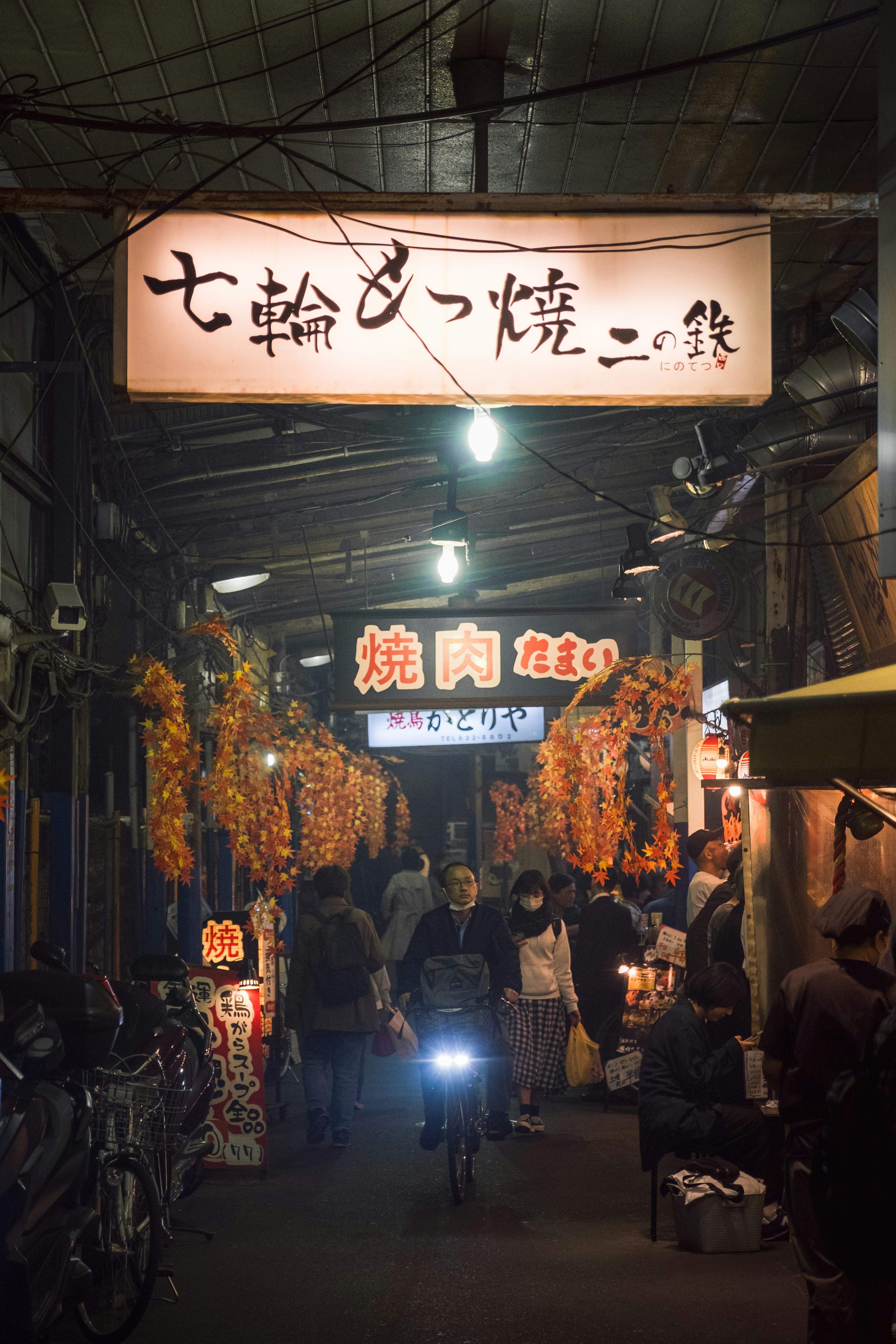 夜の屋台街に人々が行き交う風景 店の看板が明るく照らされている