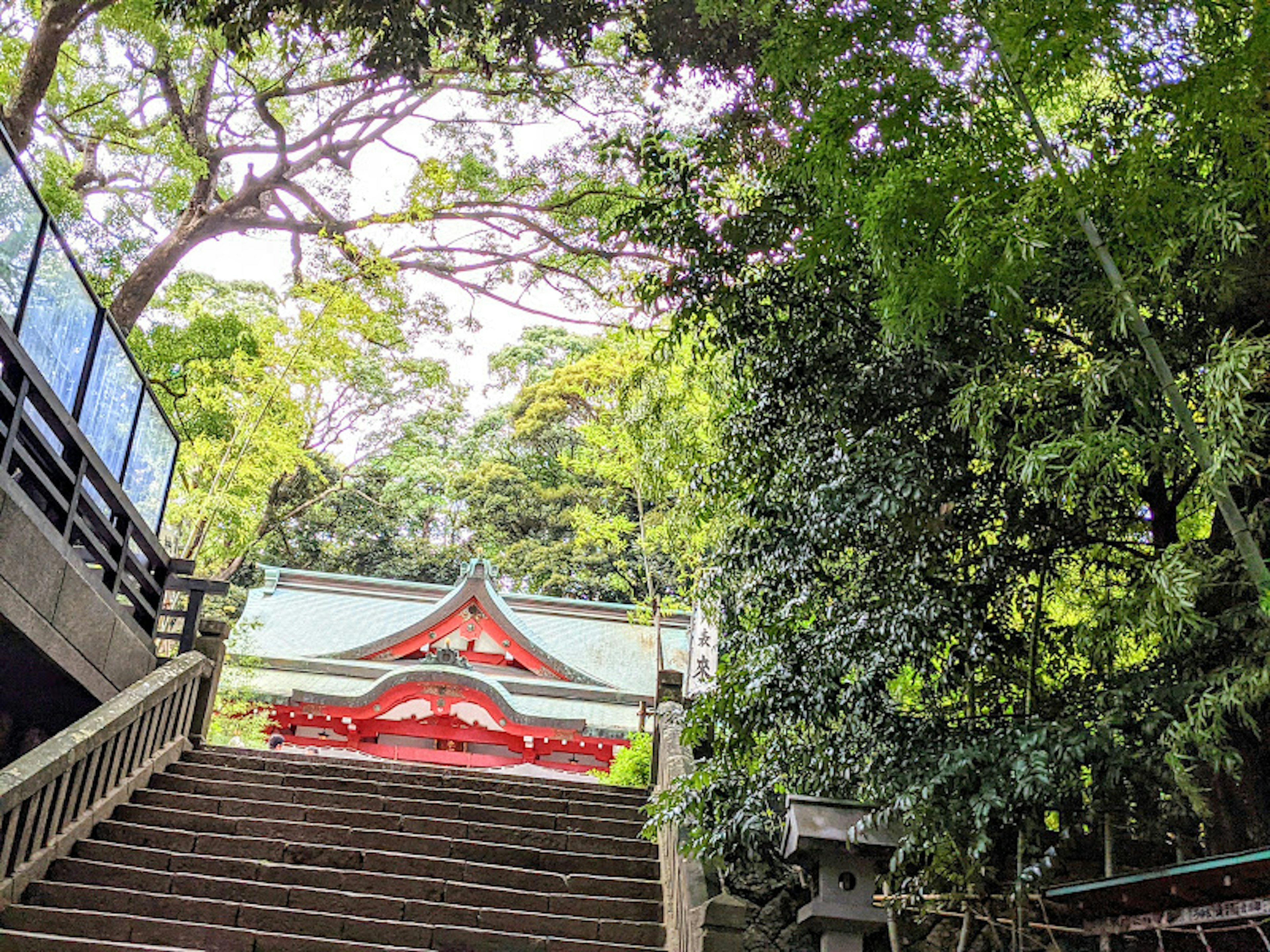 Staircase leading to a red gate surrounded by lush greenery