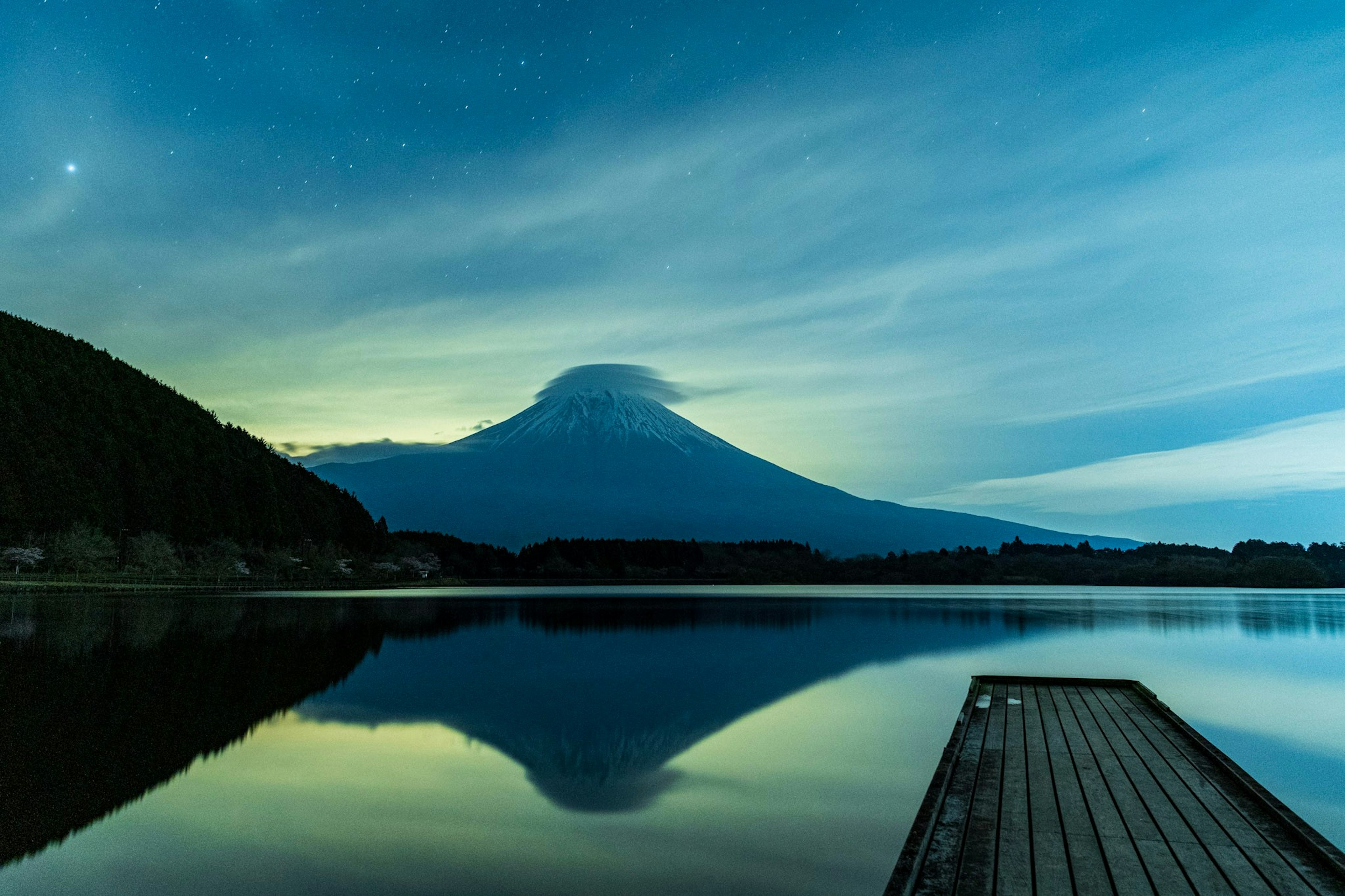 Mont Fuji se reflétant dans un lac tranquille sous un ciel étoilé