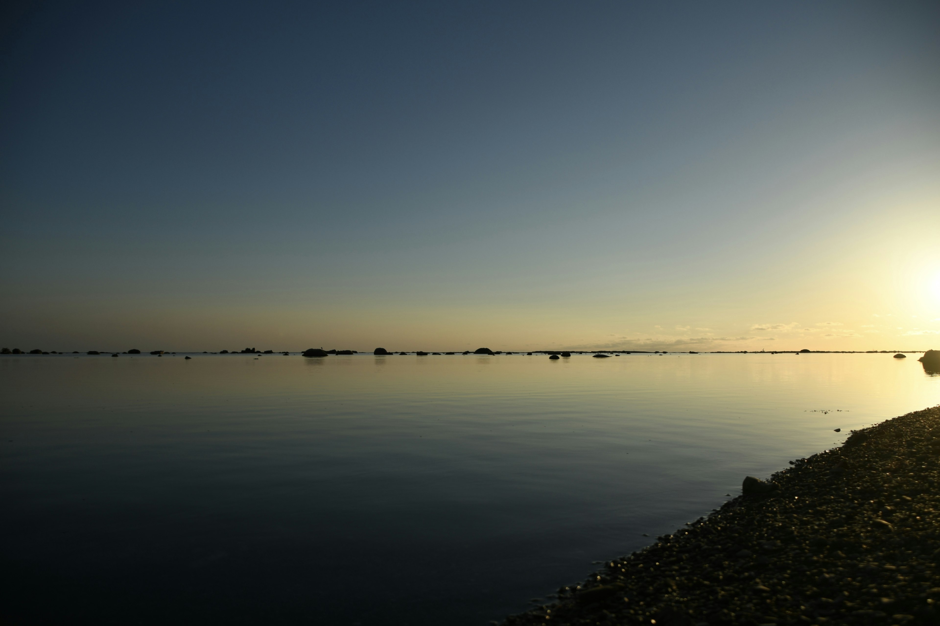 静かな水面に映る夕日の光が美しい海の風景