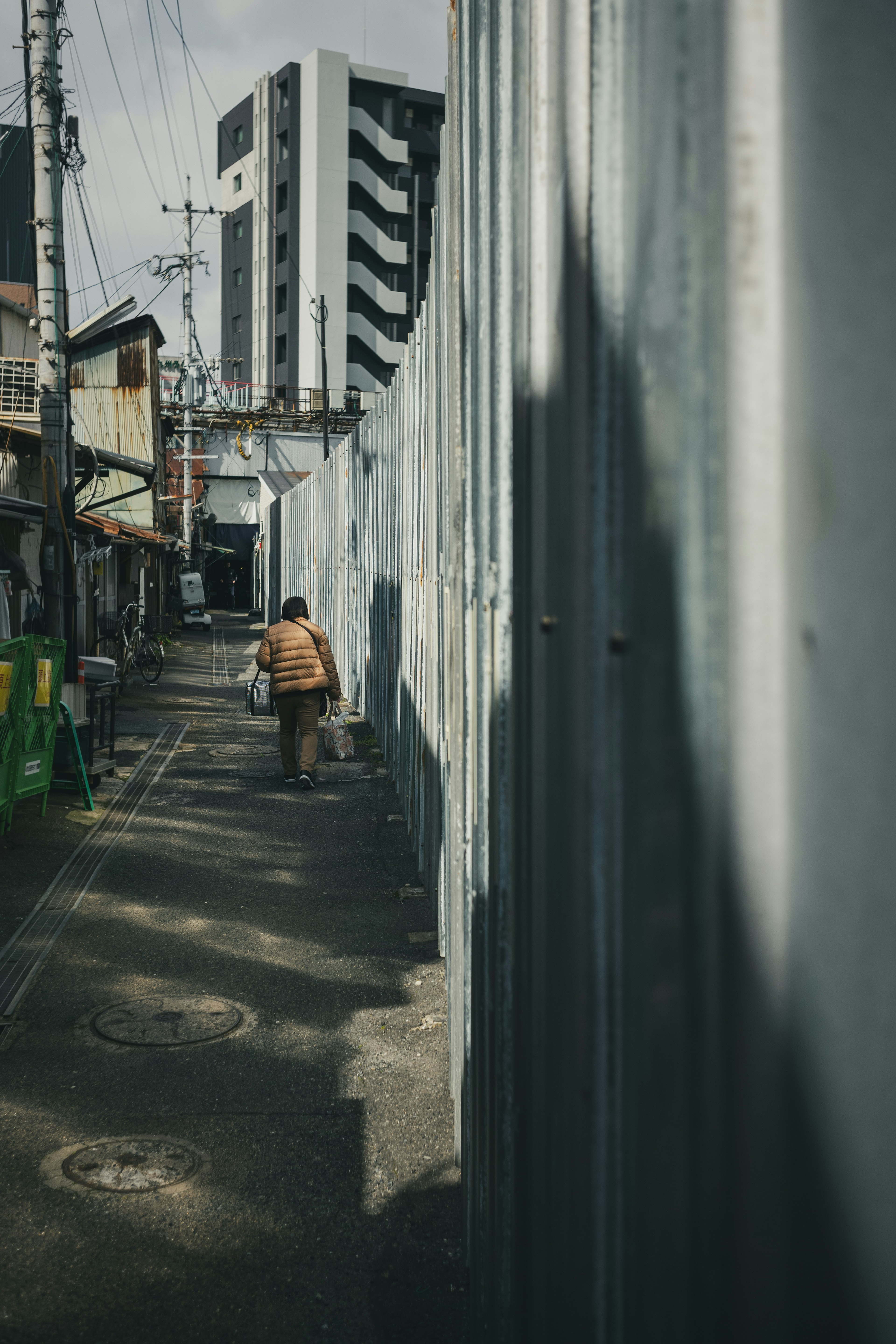 Narrow alley with metal walls and the shadow of a high-rise building