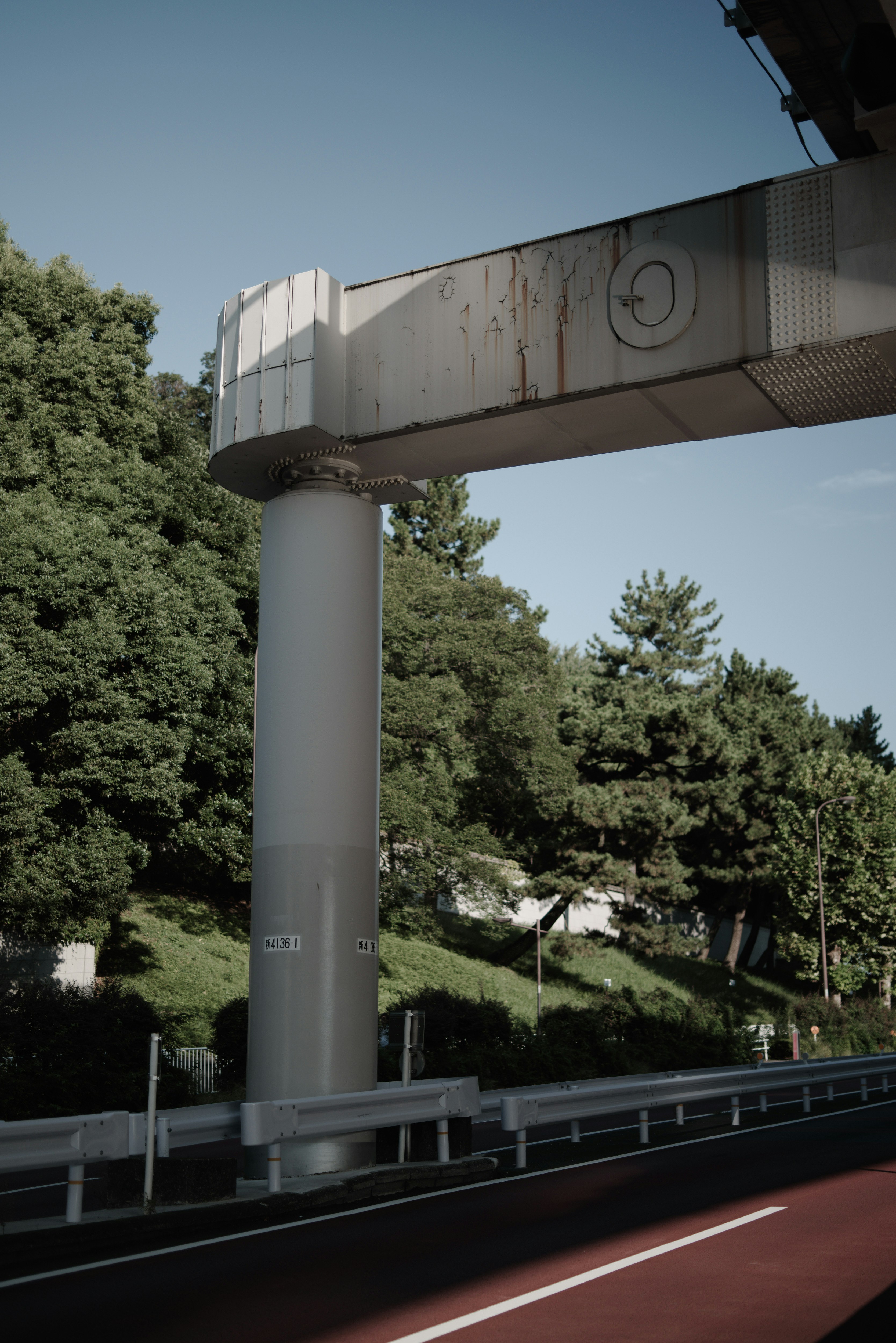 A view of a highway overpass column with green trees in the background