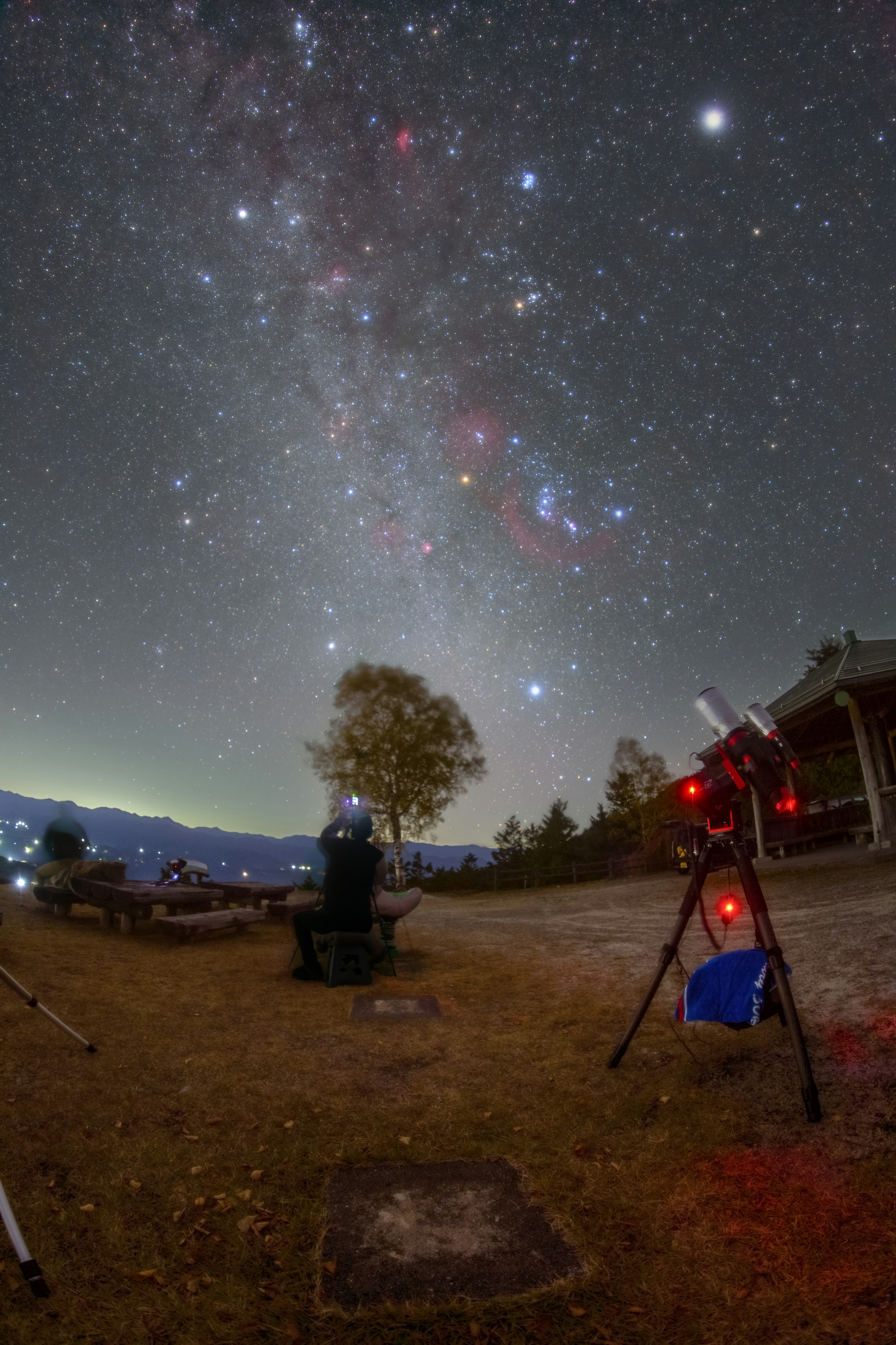 星空の下で望遠鏡を使用している人物と美しい天の川が見える夜の風景