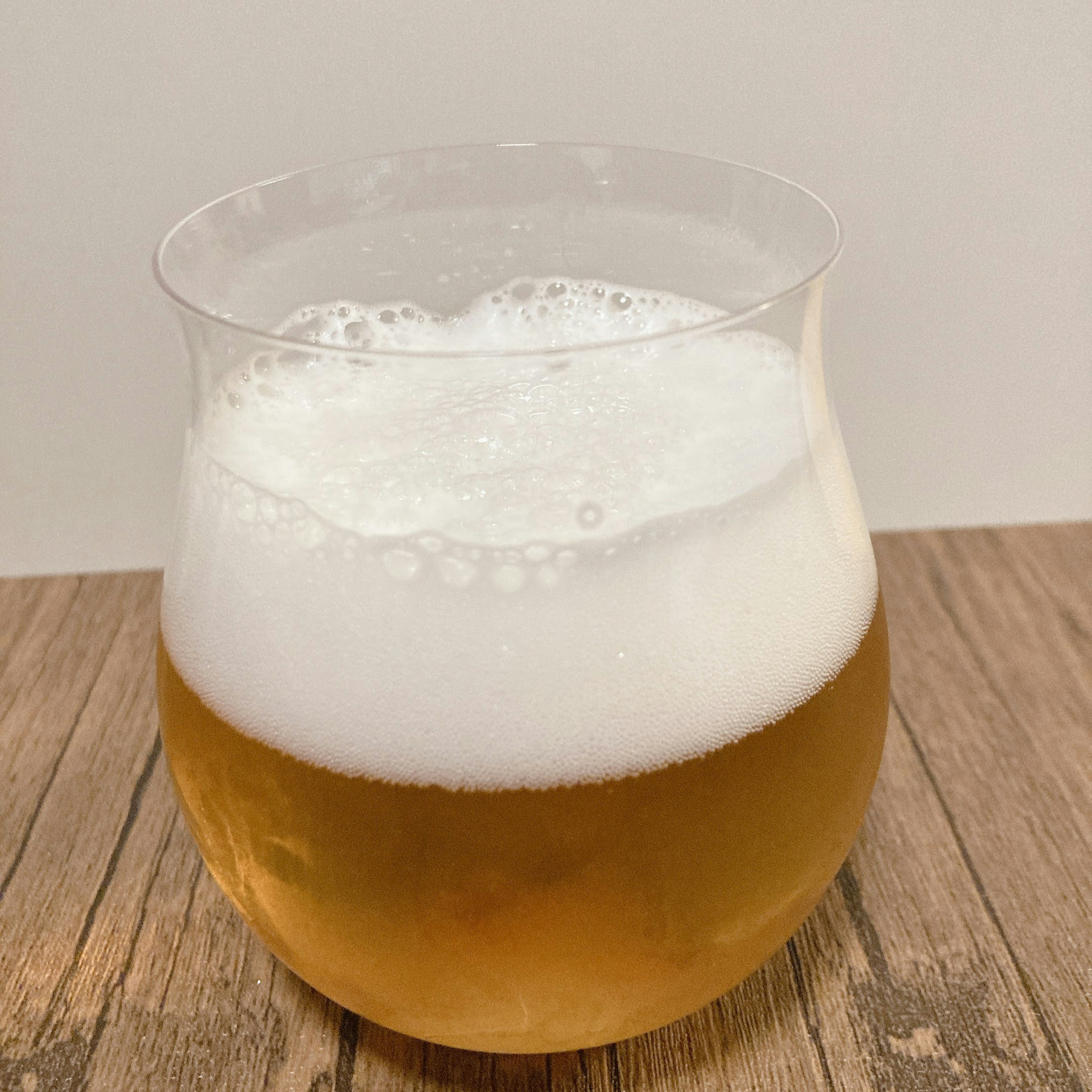 Un verre rempli de bière mousseuse sur un fond neutre