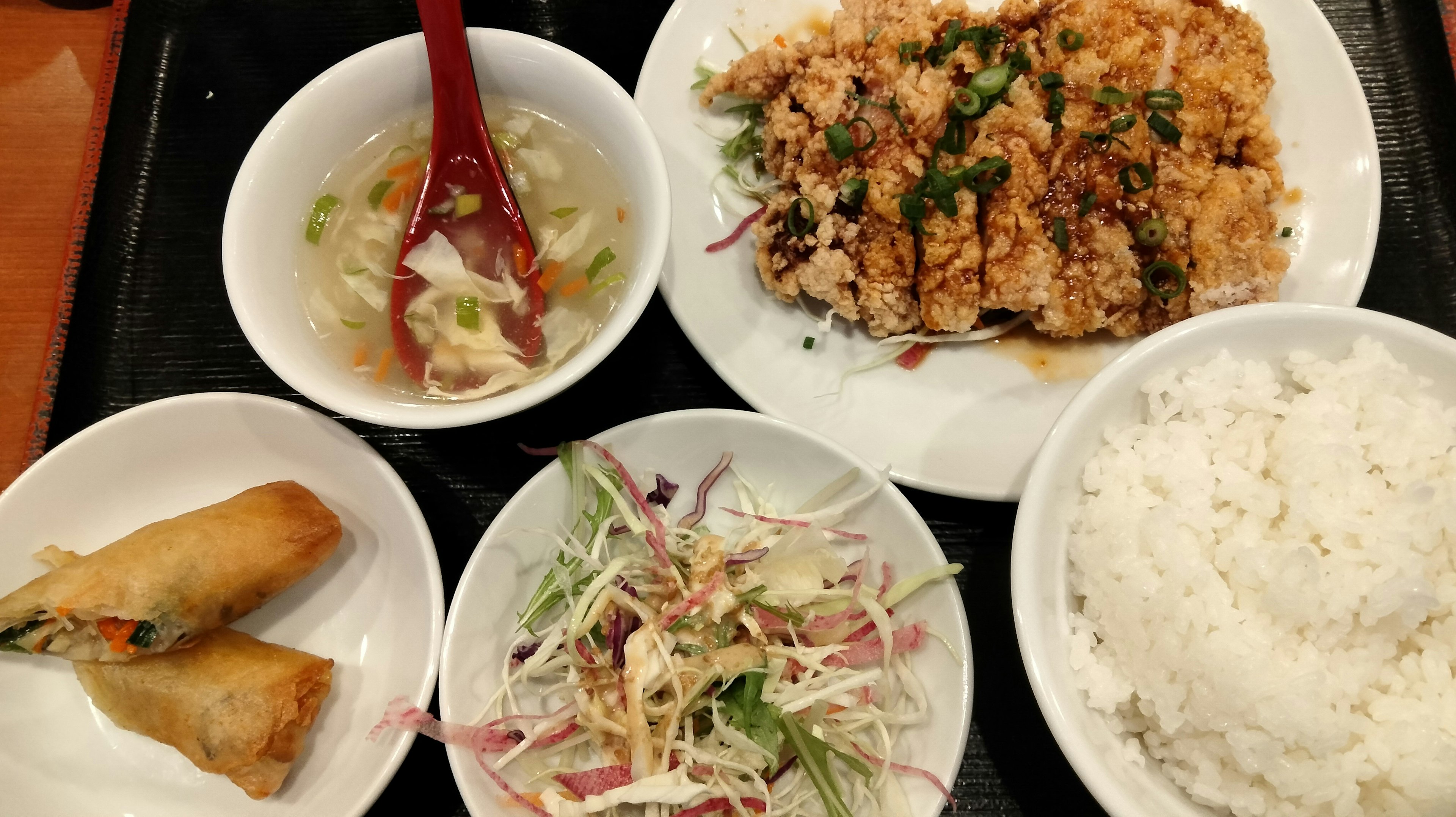 A colorful plate featuring rice salad spring rolls and a soup bowl