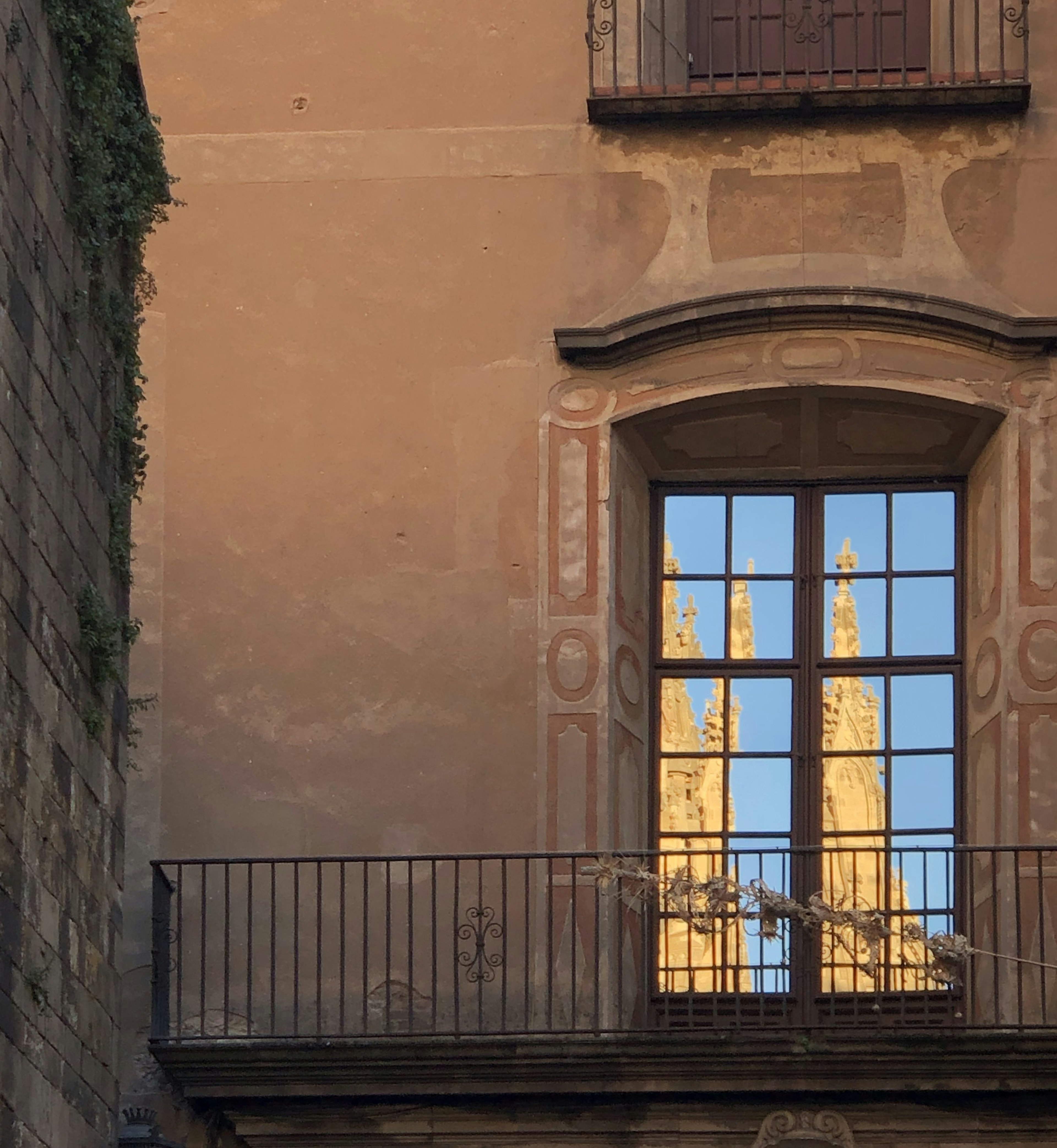 Reflejo de las agujas de una iglesia en la ventana de un edificio antiguo