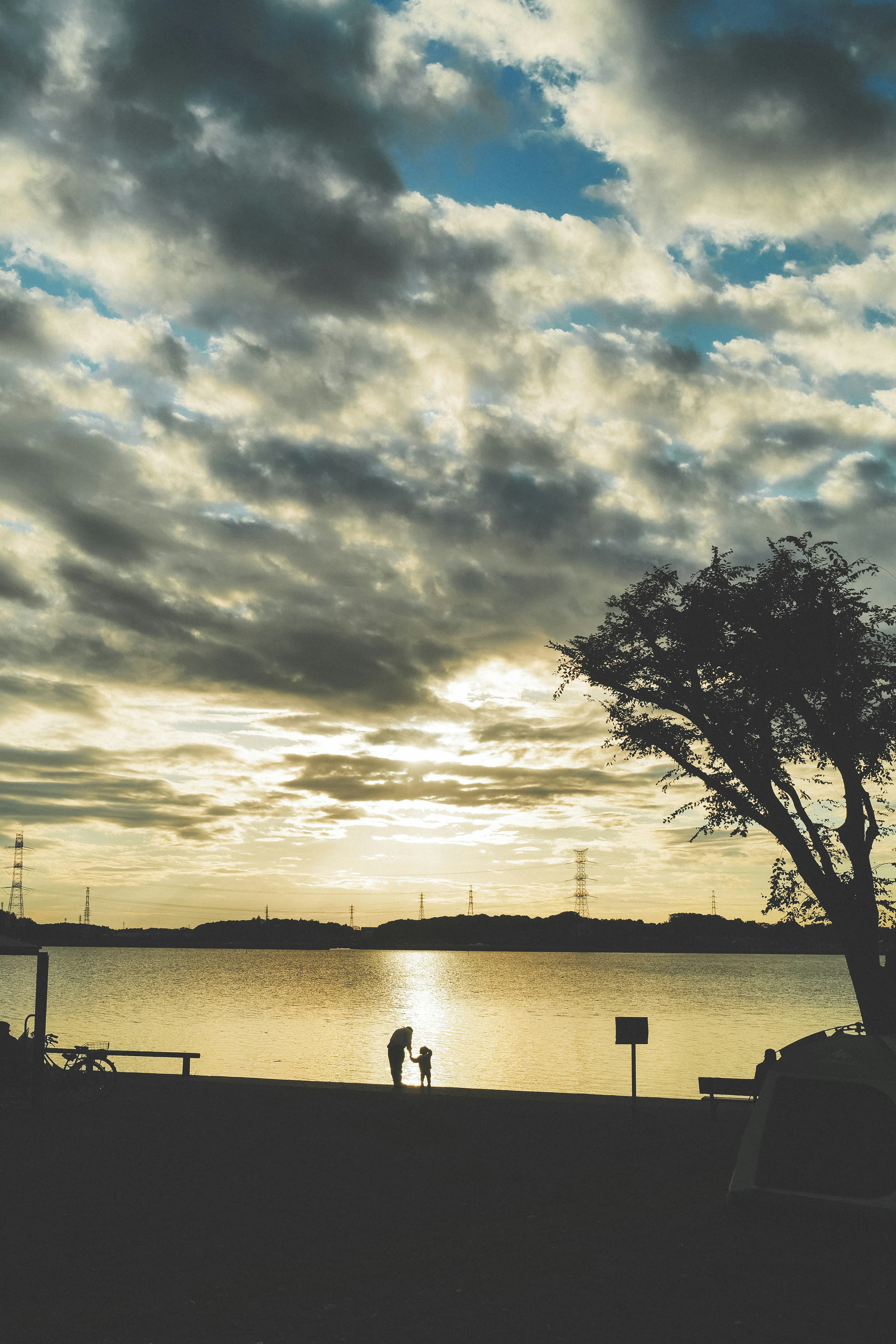 夕日を背景にした湖のほとりで人々が立っているシルエット