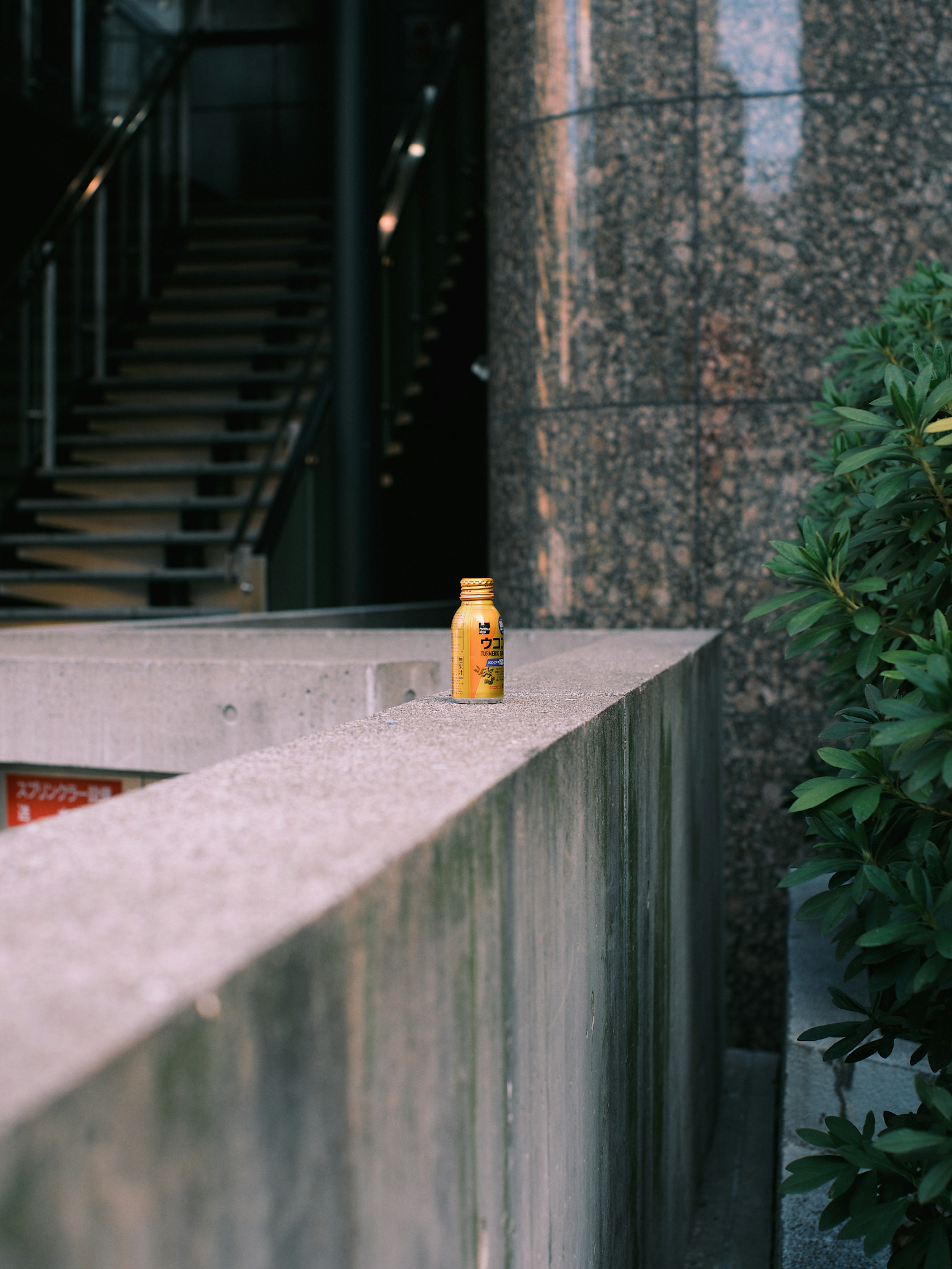 Gelbe Getränkeflasche auf einem Betonrand in der Nähe von Treppen