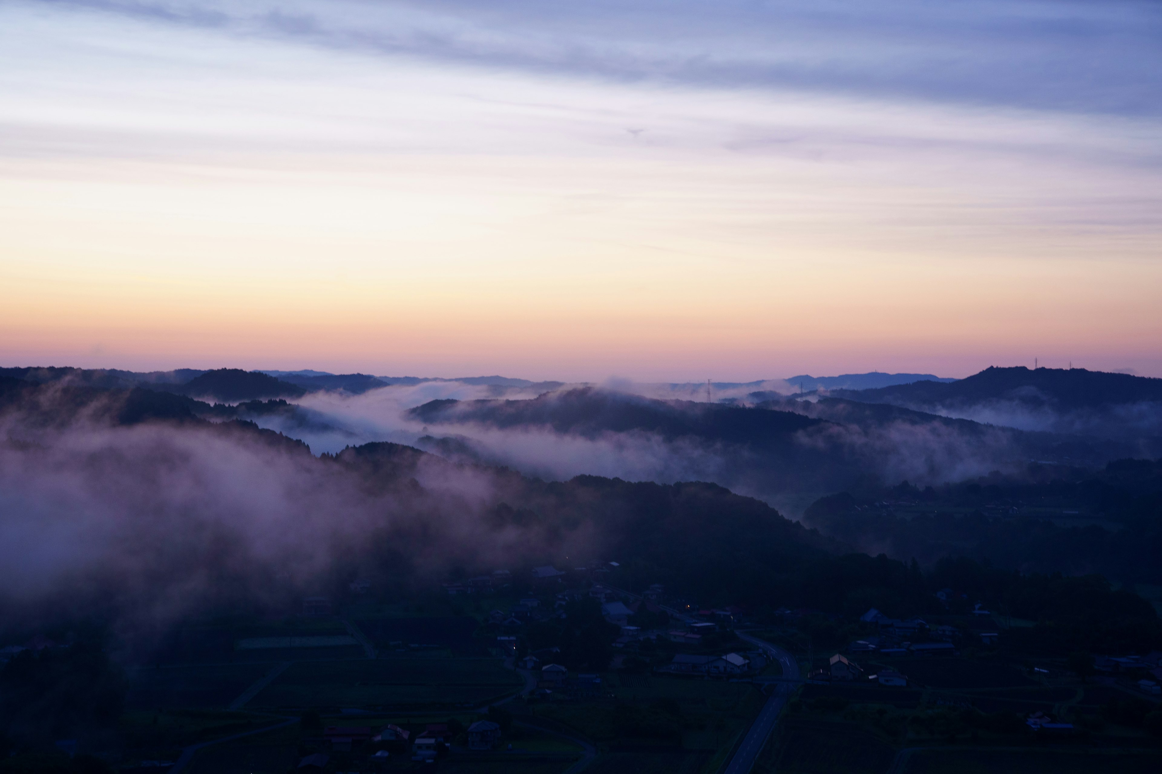 霧に包まれた丘陵と夕焼けの空の風景