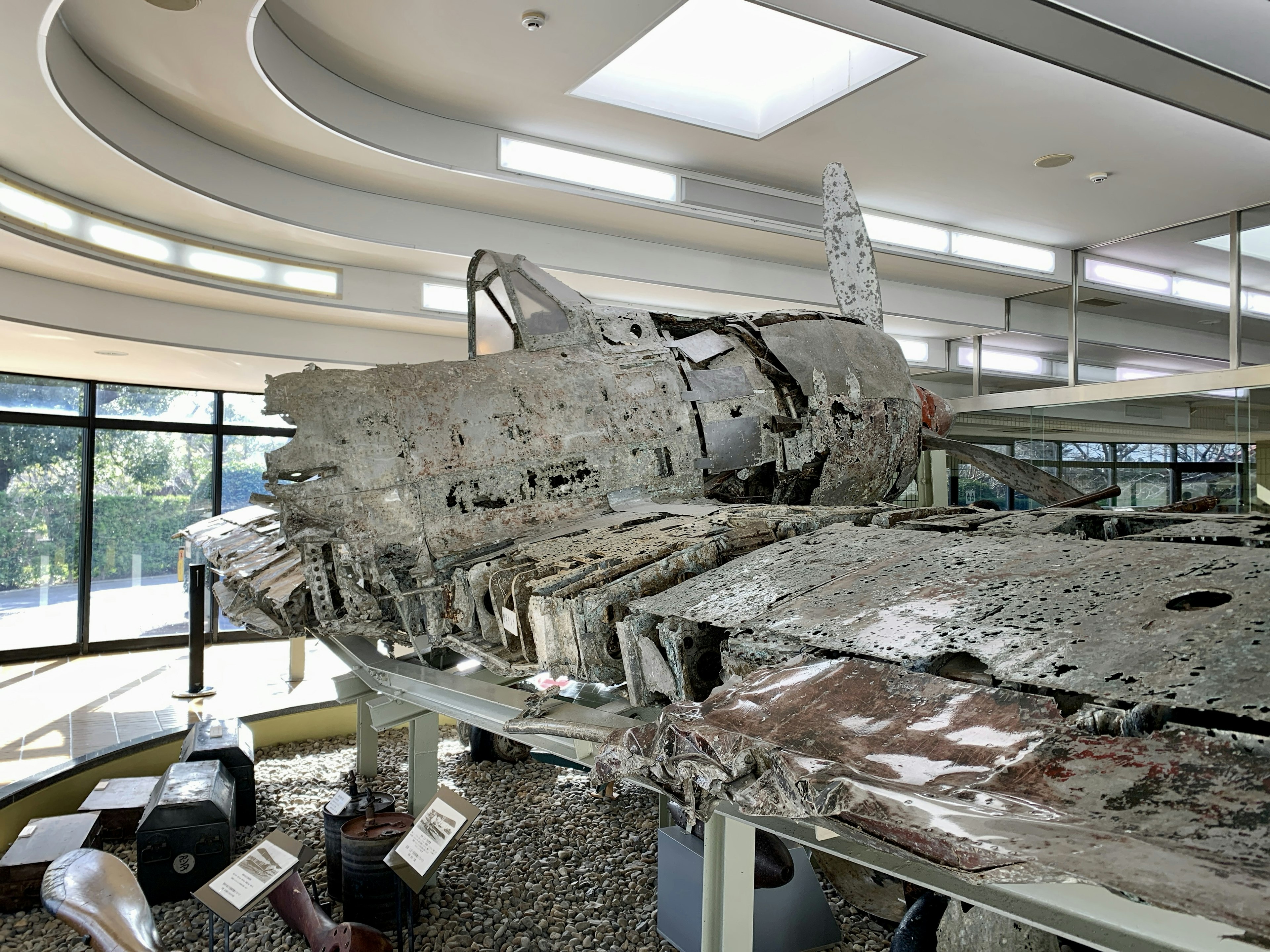 Ausstellung eines Flugzeugwracks mit sichtbarer Metallkorrosion und Schäden in einem Museum