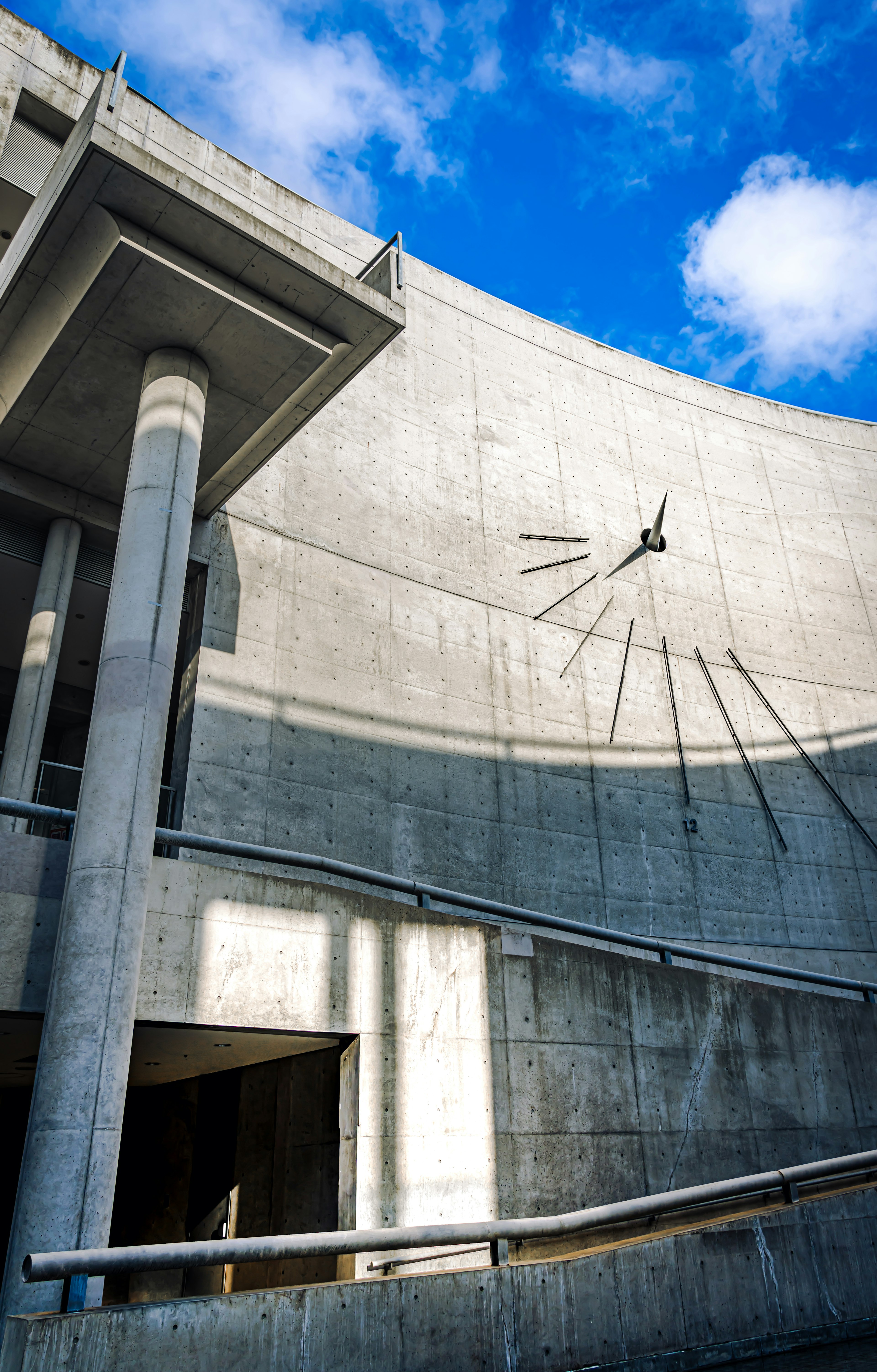 Lado de un edificio de concreto con sombras grandes y cielo azul