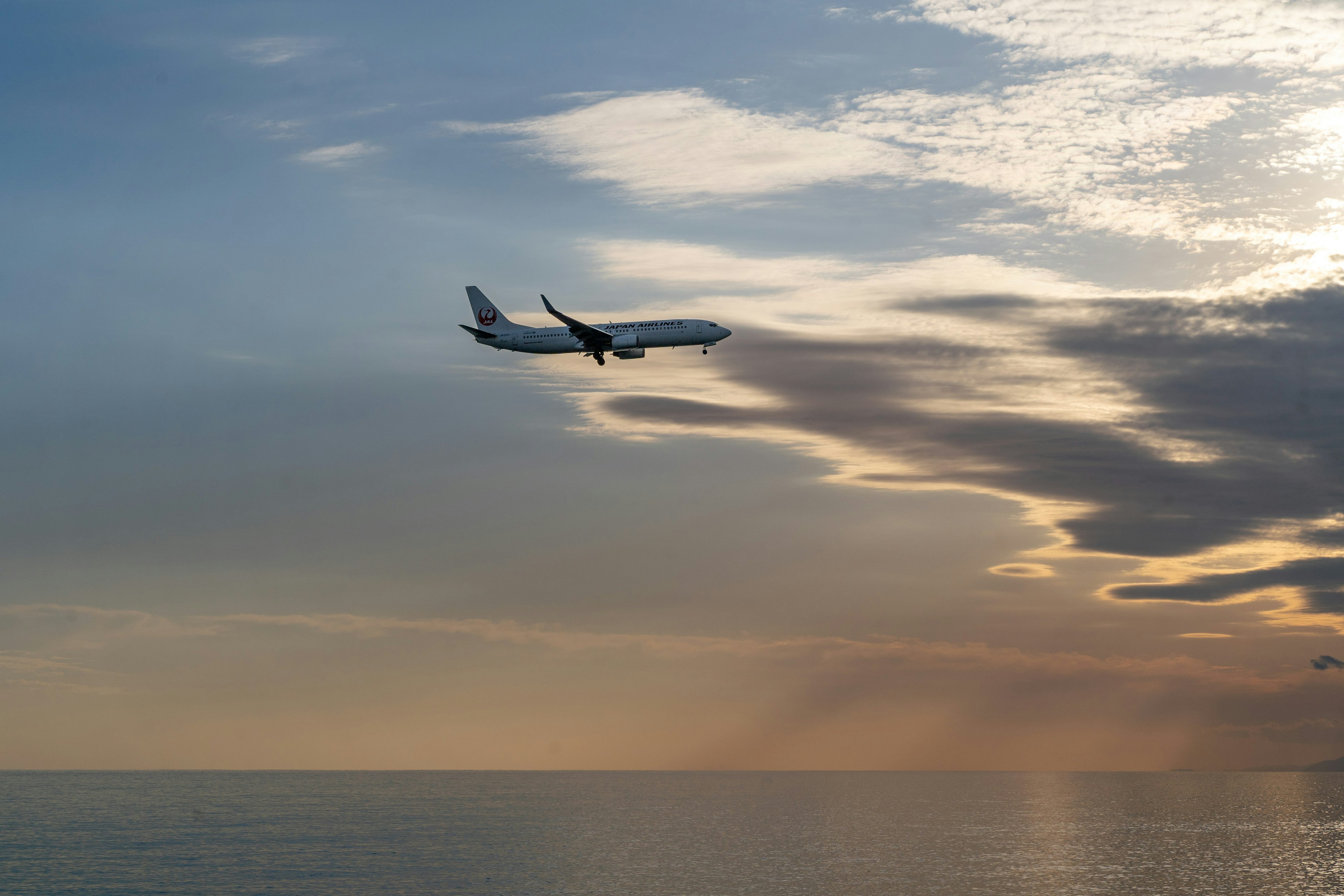 海の上を飛ぶ飛行機と美しい夕焼けの空