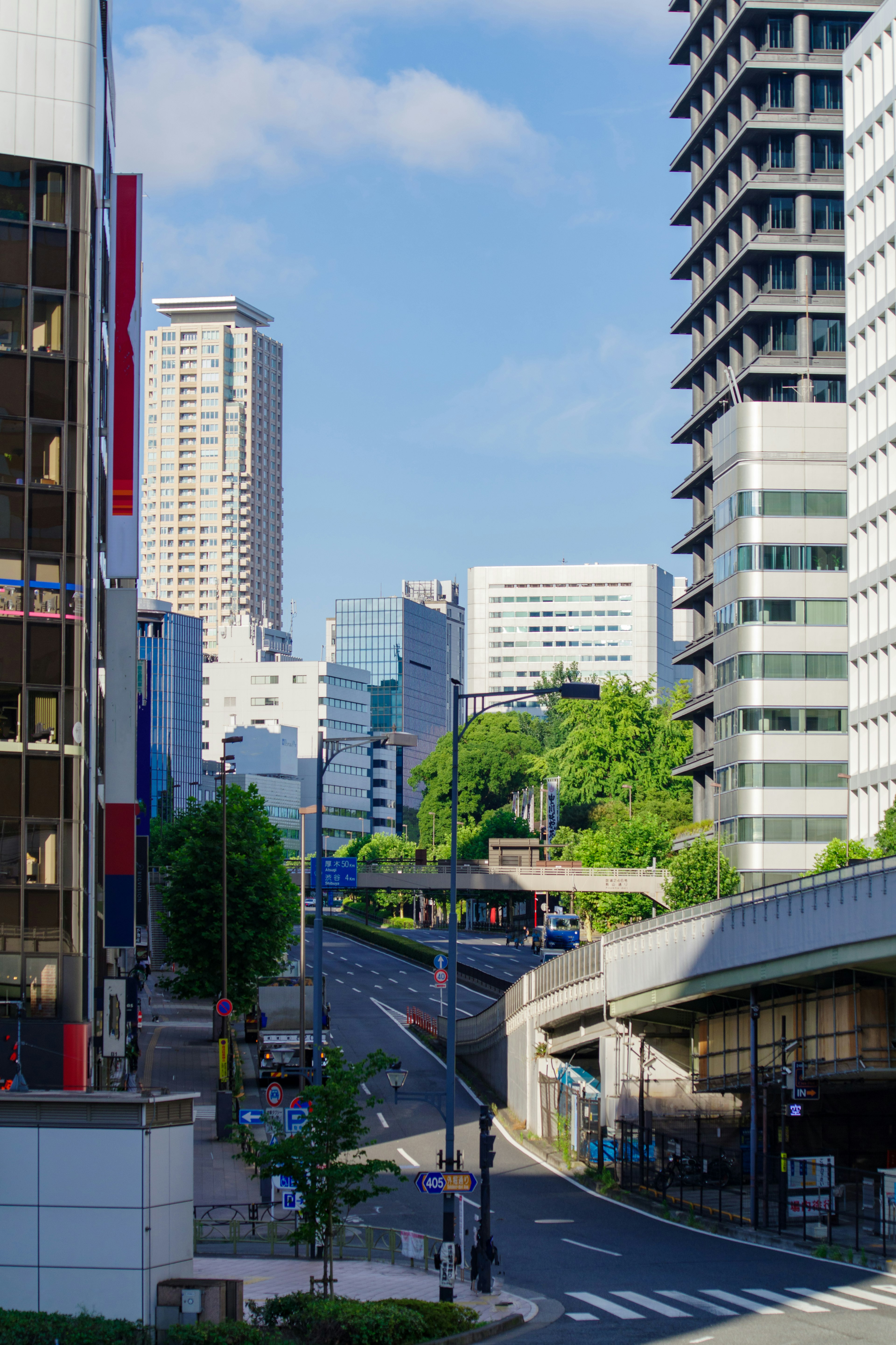 东京的城市景观，高楼大厦和蓝天，路边有绿色树木