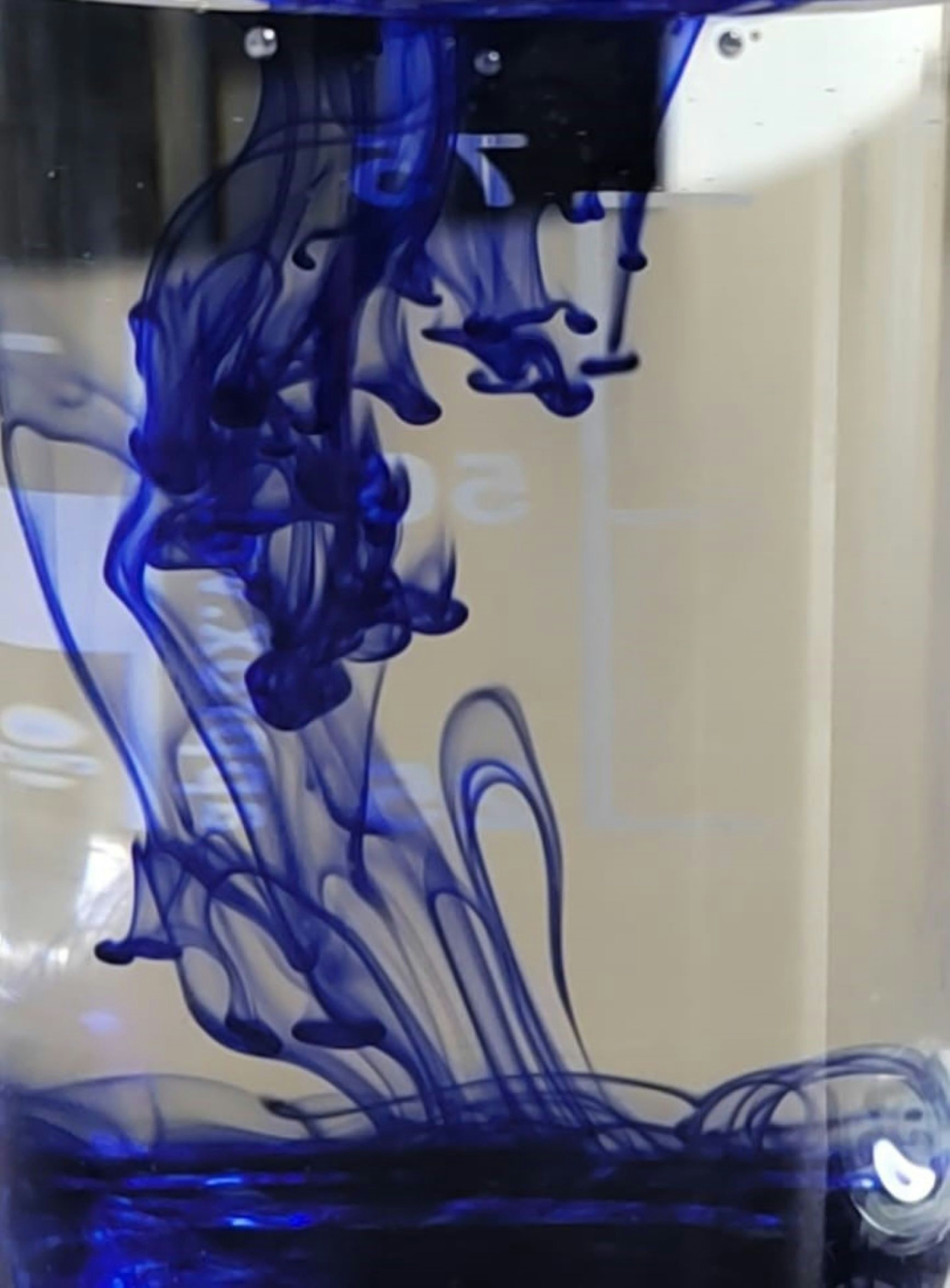 Encre bleue tourbillonnant dans l'eau créant des motifs complexes