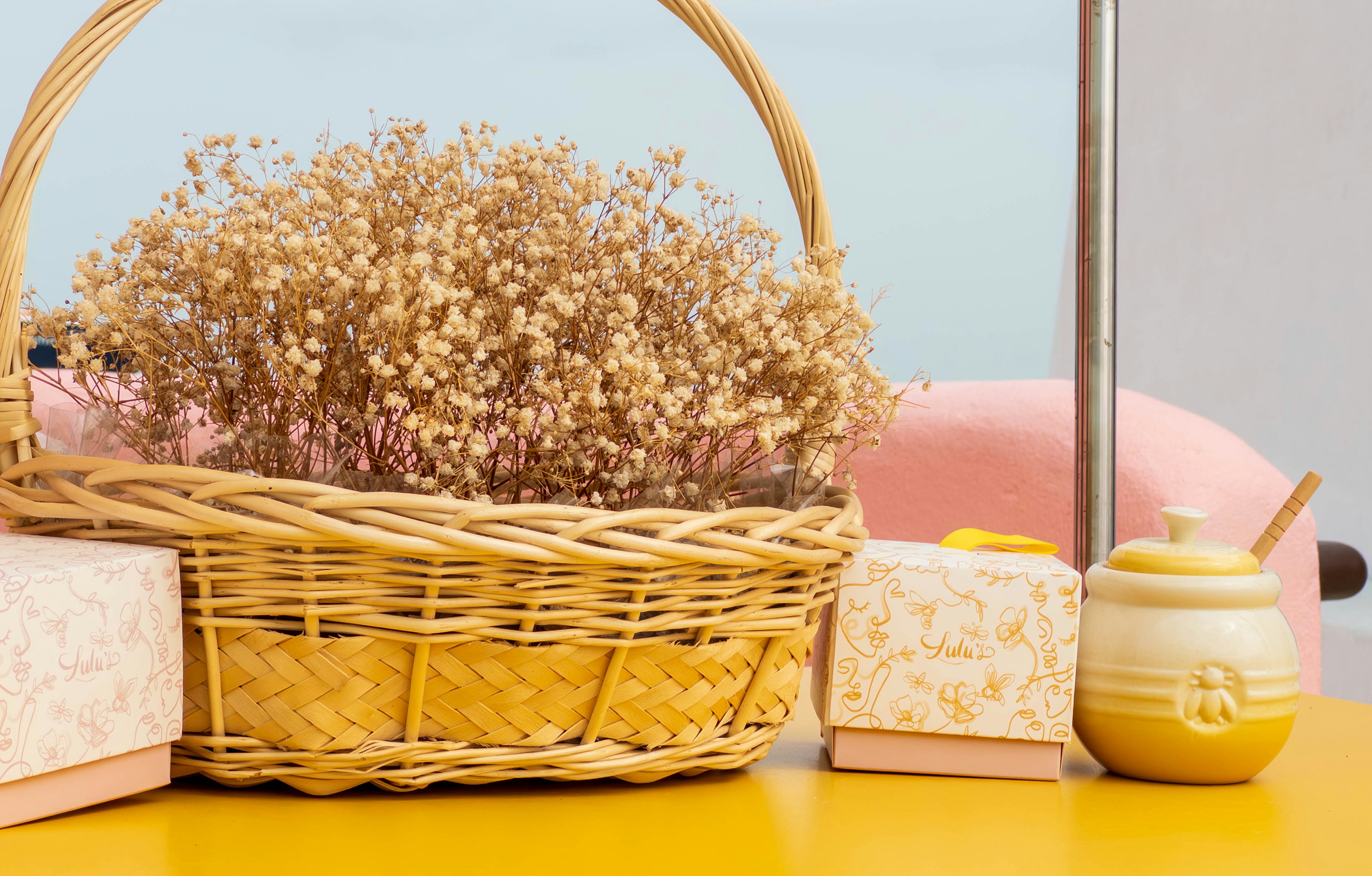 Un petit panier en osier avec des fleurs séchées sur une table jaune