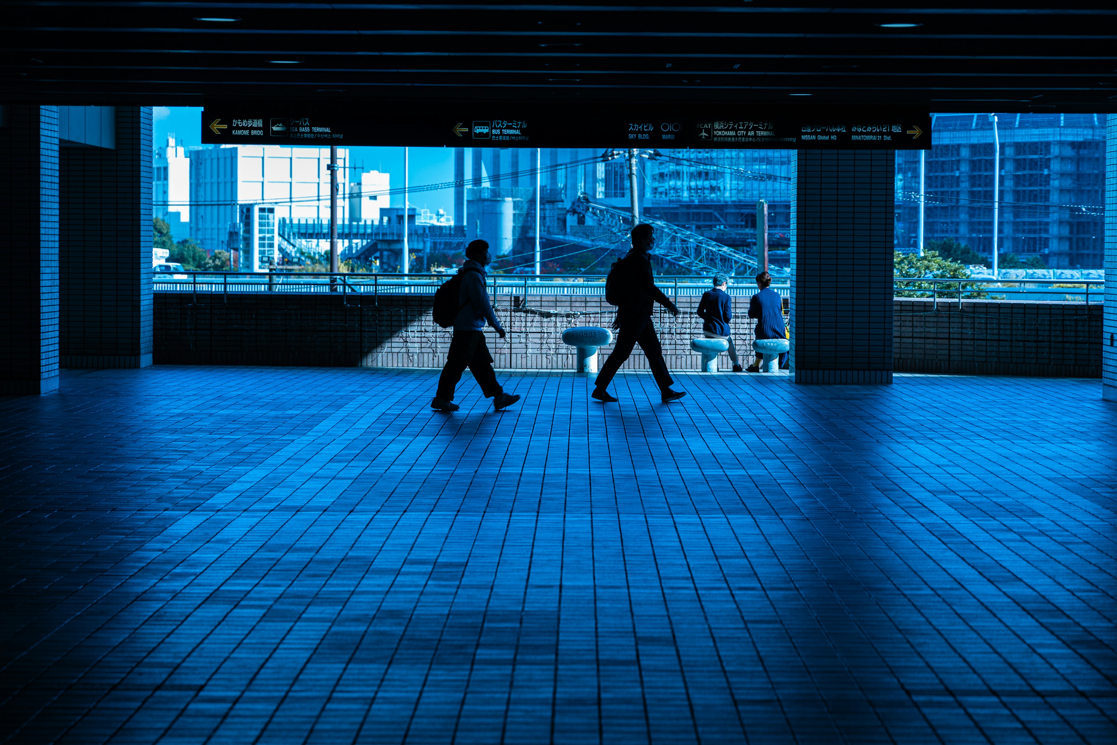 Siluetas de personas caminando en un espacio urbano azul