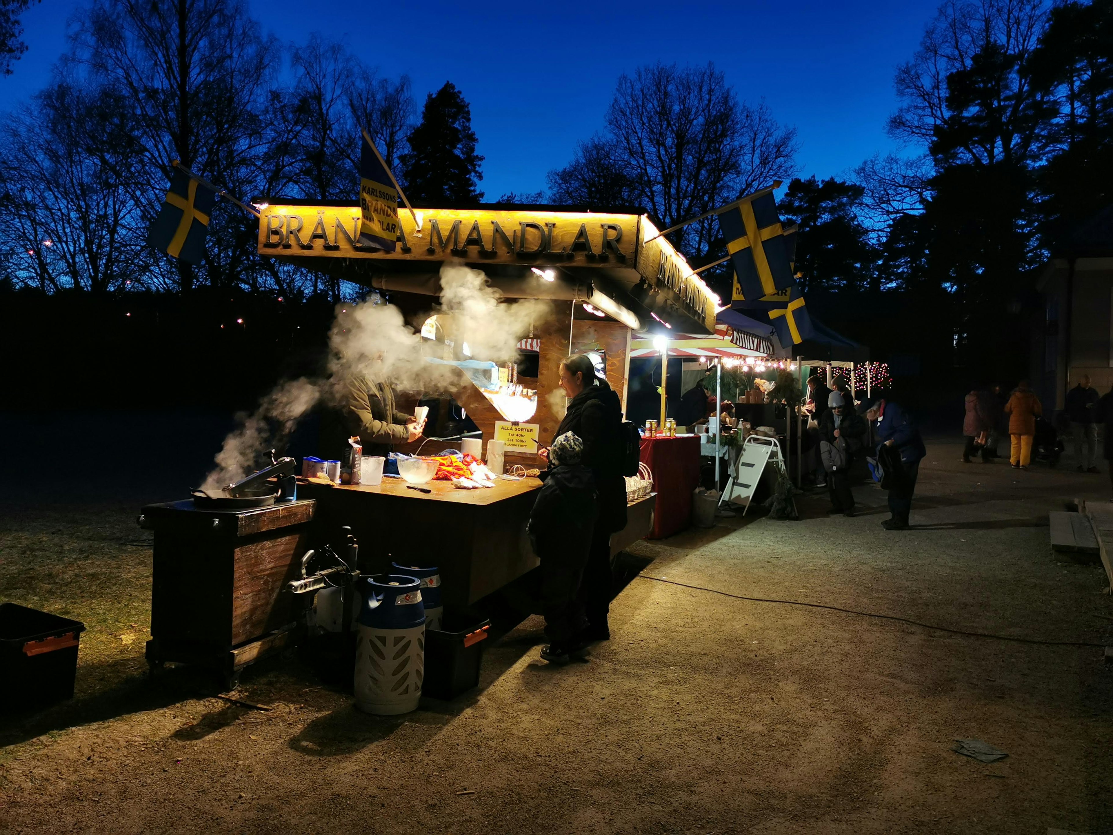 Puesto de comida nocturno con personas cocinando y vapor que se eleva