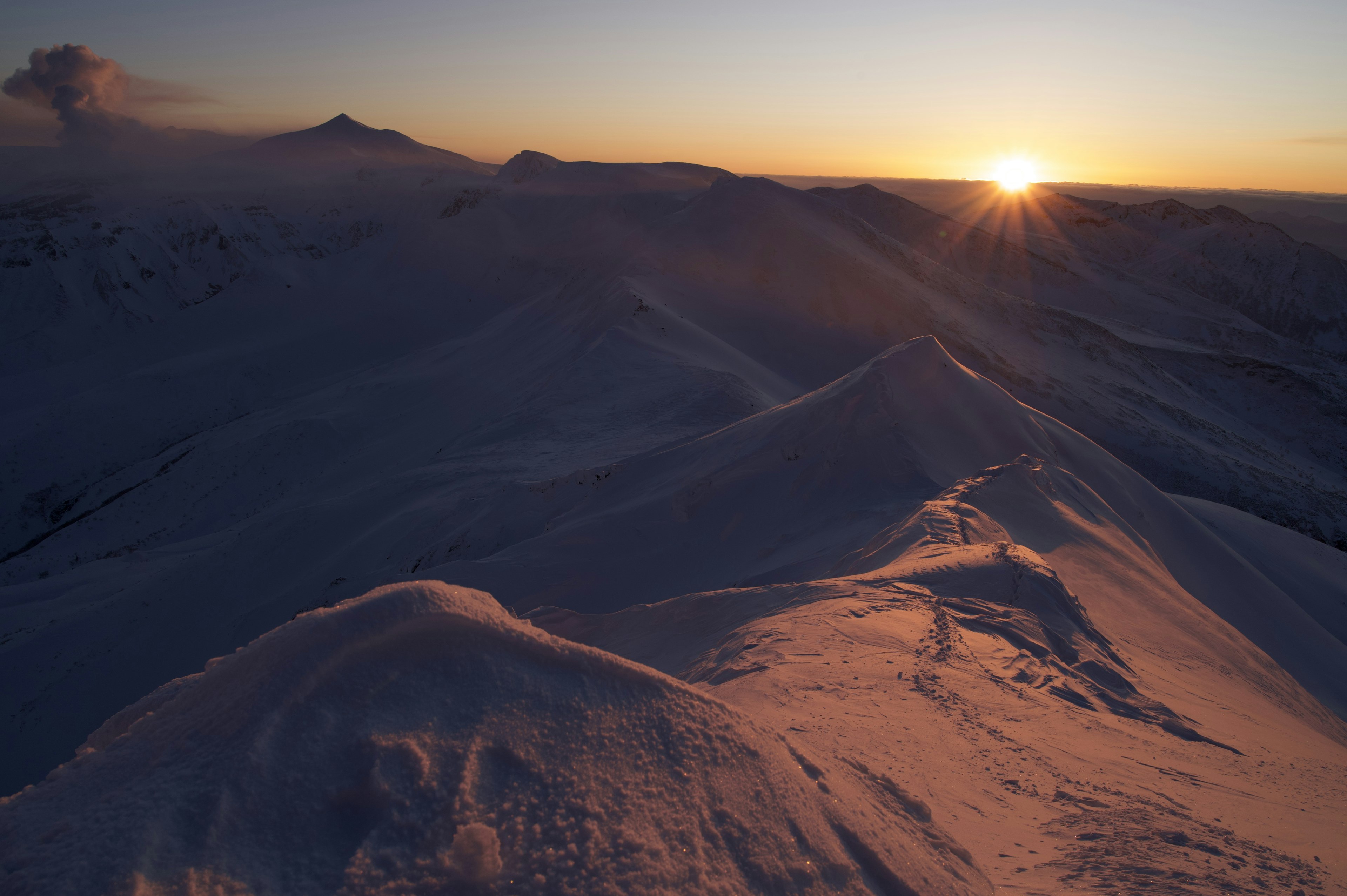 Amanecer sobre picos de montaña cubiertos de nieve