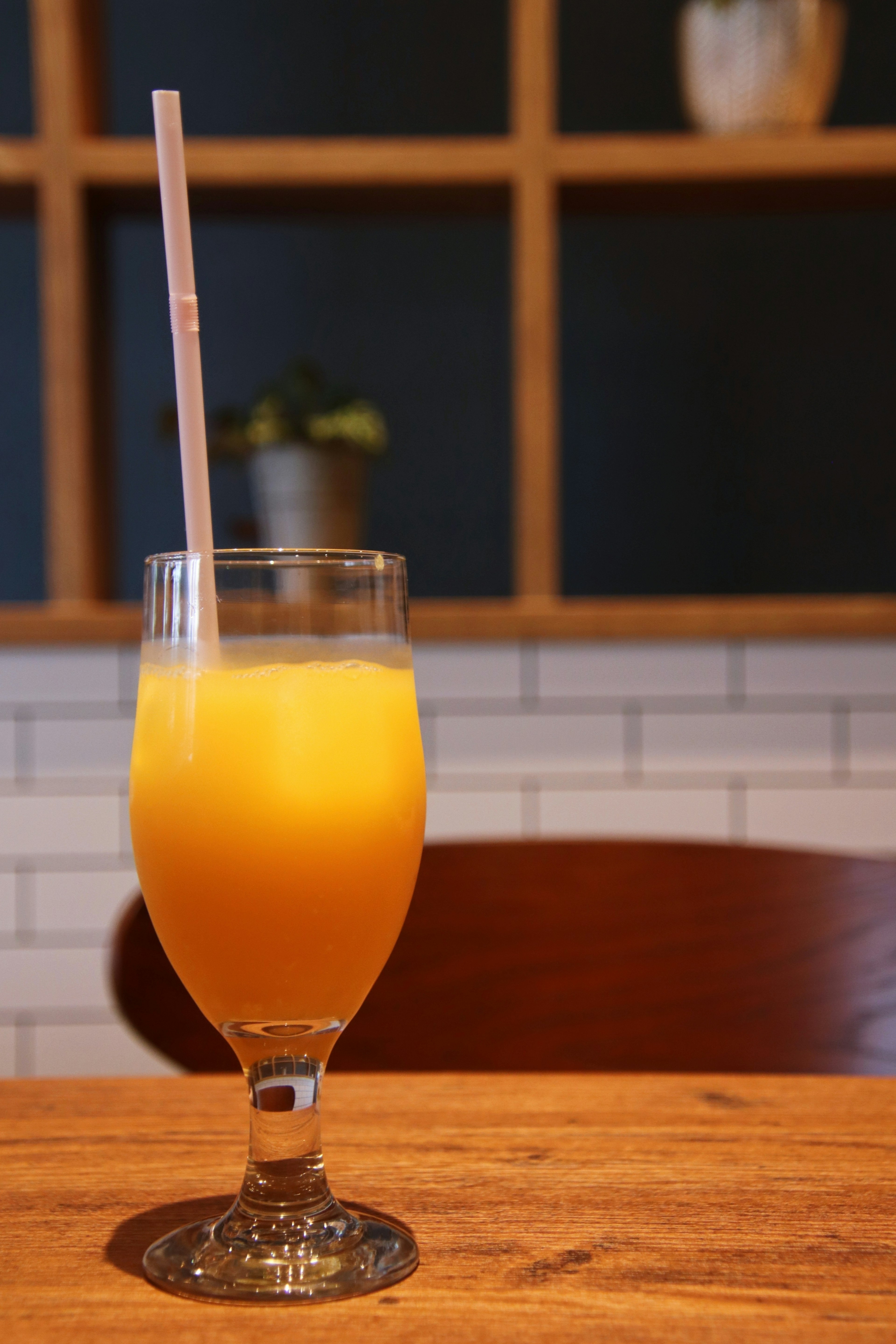 Un vaso de jugo de naranja con una pajita sobre una mesa de madera