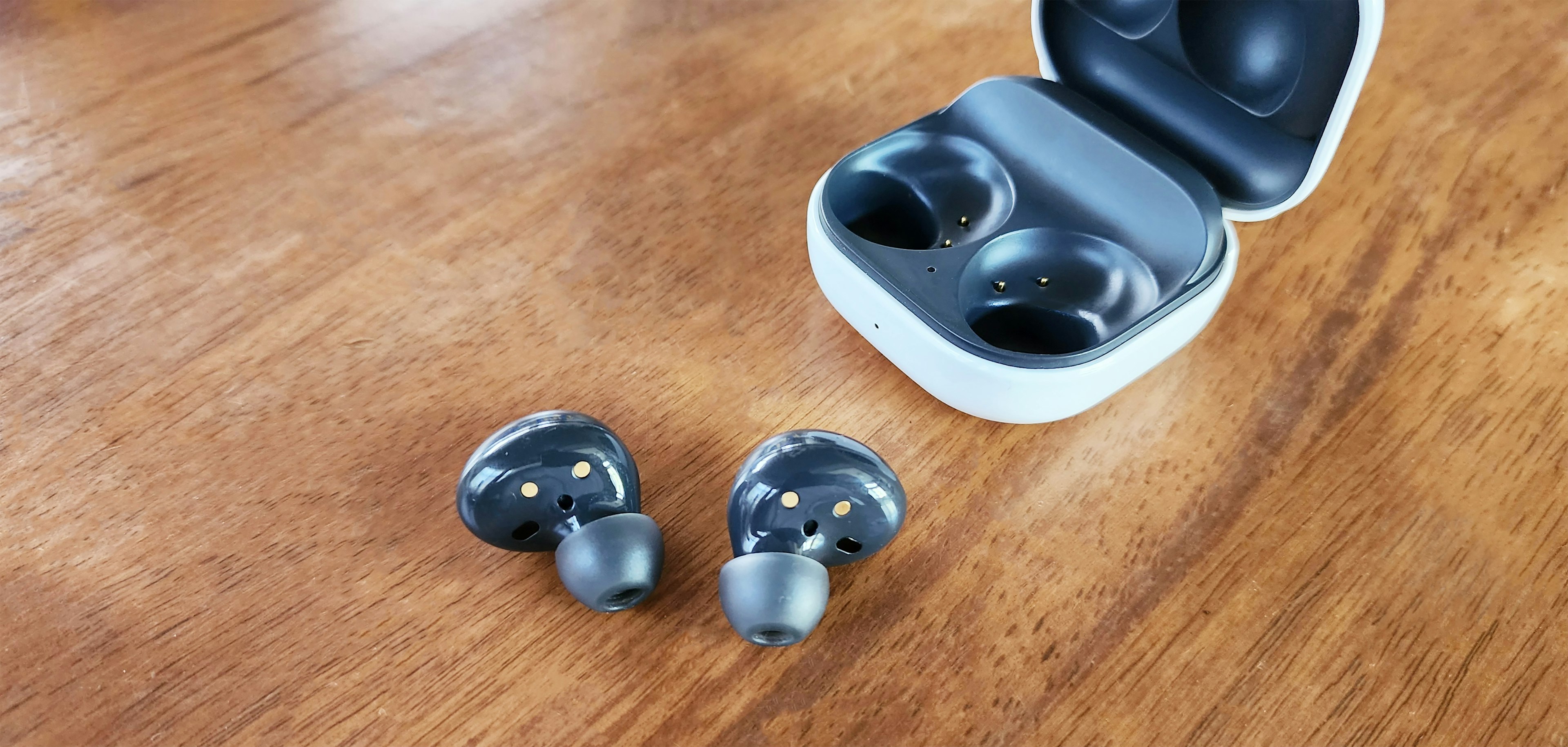 Wireless earbuds and charging case on a wooden table